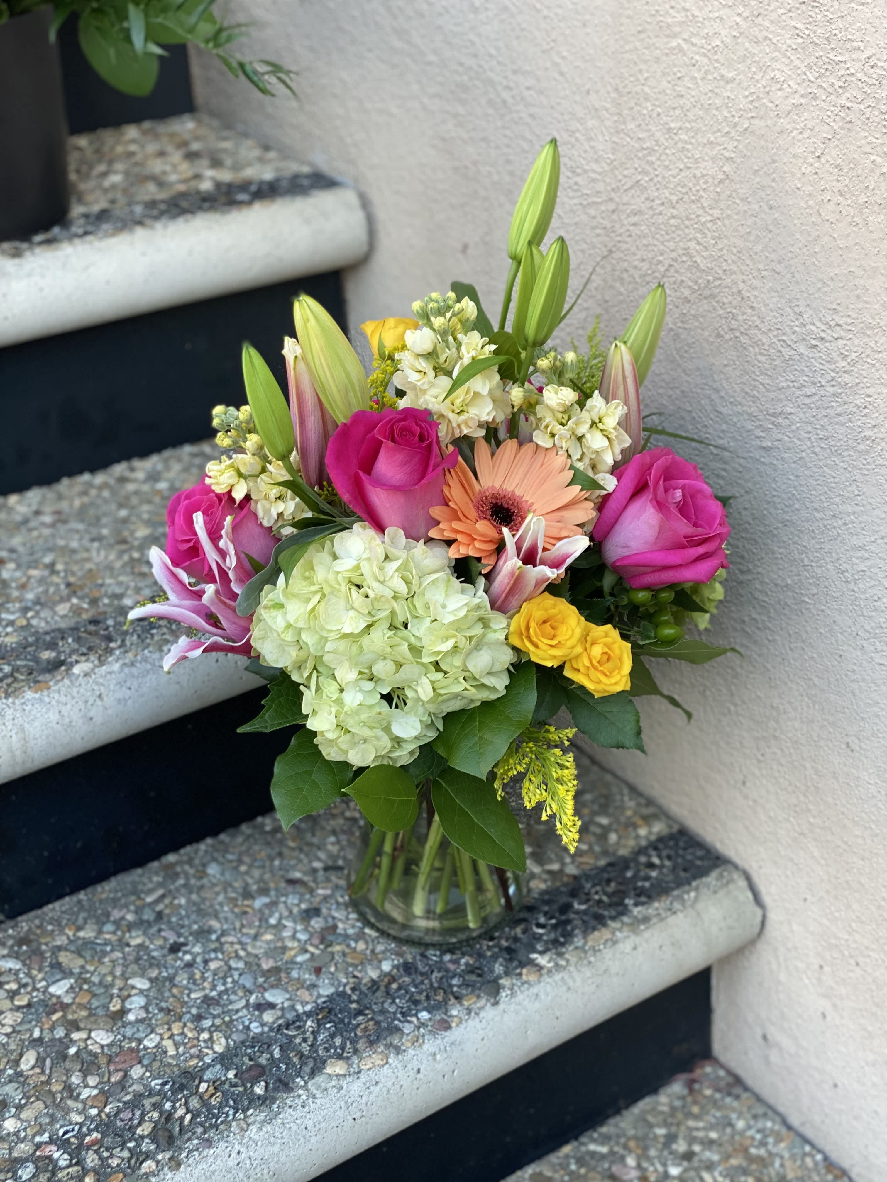 Mixed bouquet of pink roses, lilies, and hydrangea in a glass vase