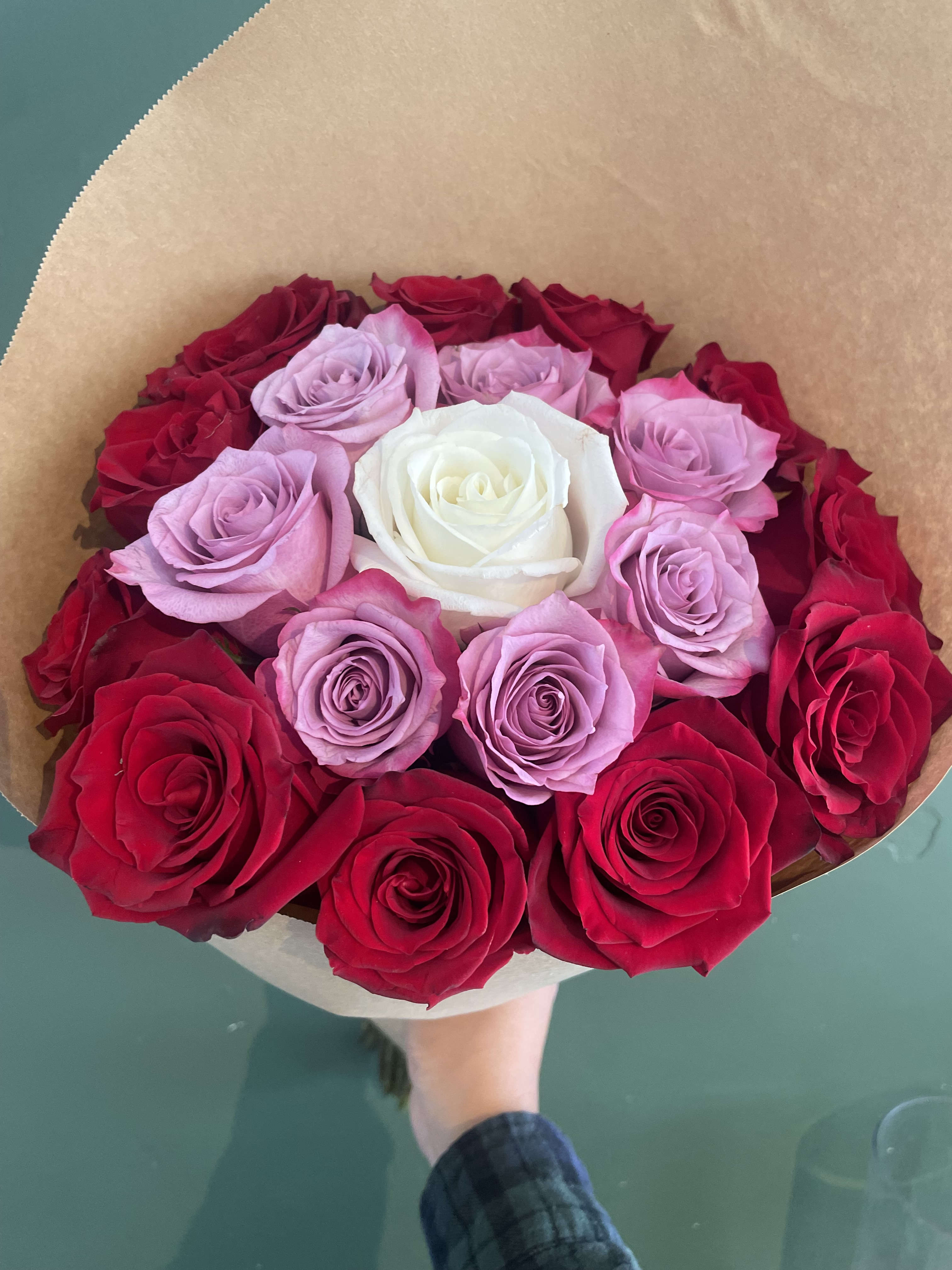 Bouquet of red, pink, and white roses wrapped in brown paper