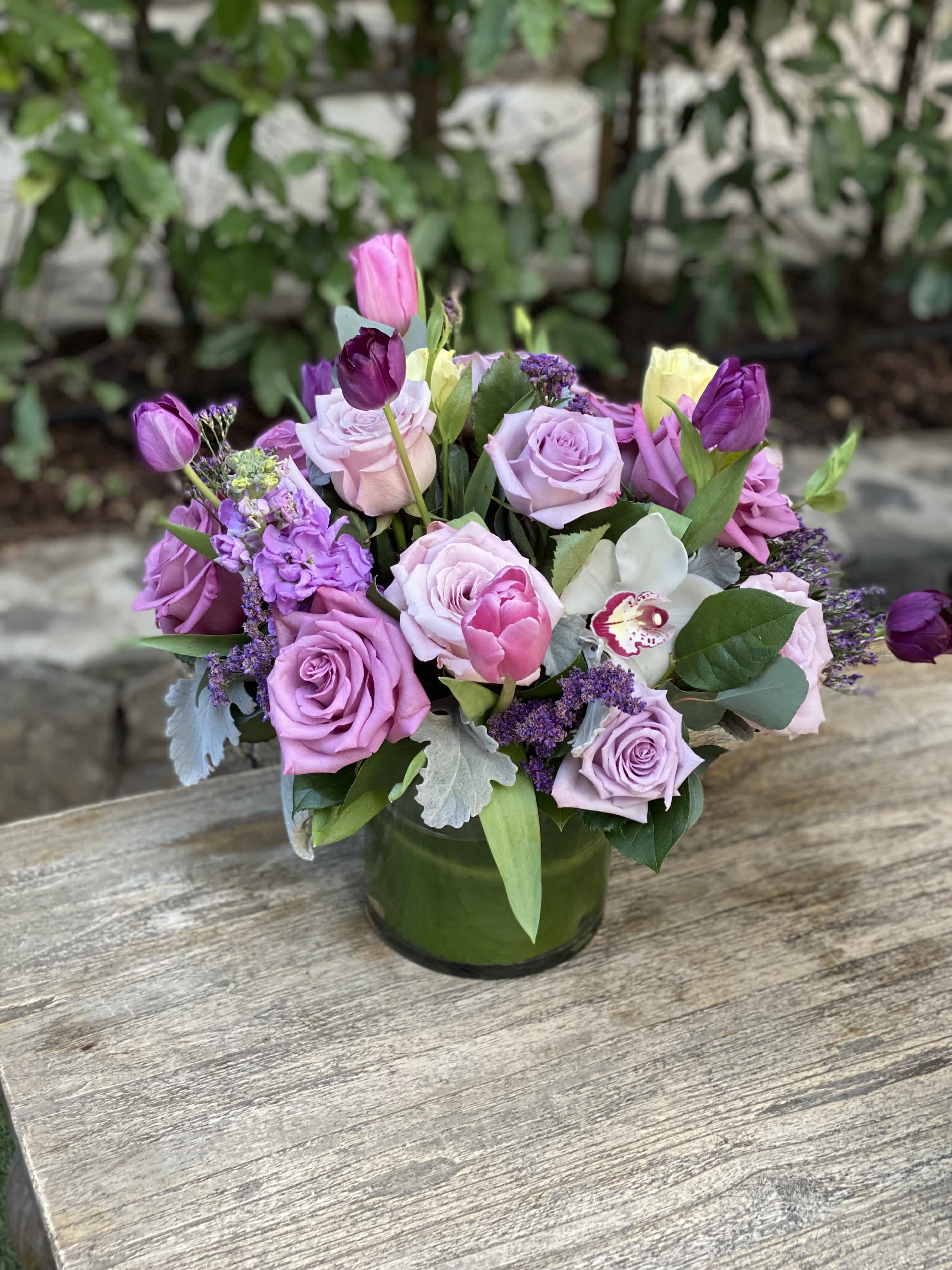 Lavender rose and tulip bouquet in a green glass vase