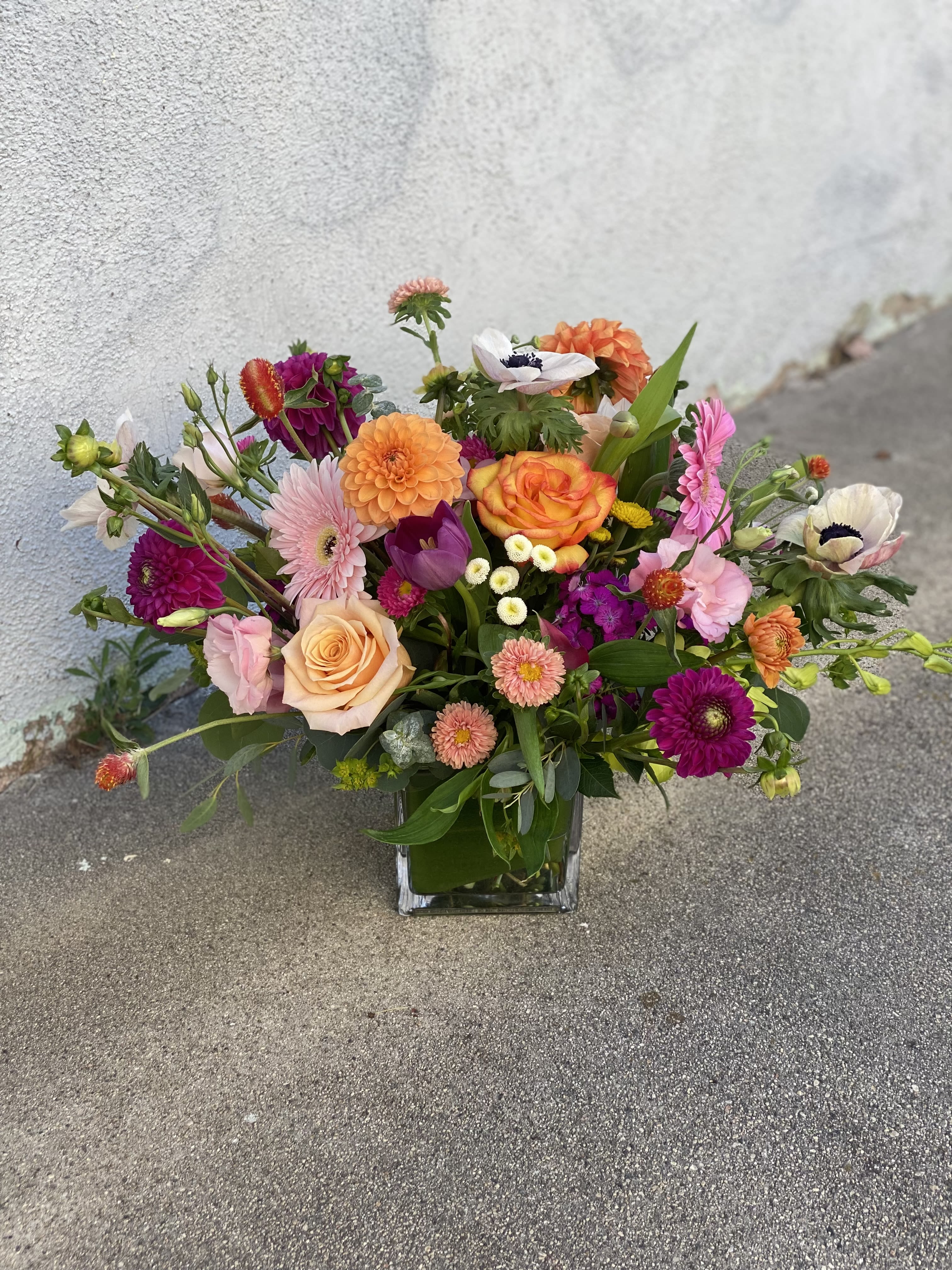 Mixed bouquet of colorful flowers in a square glass vase