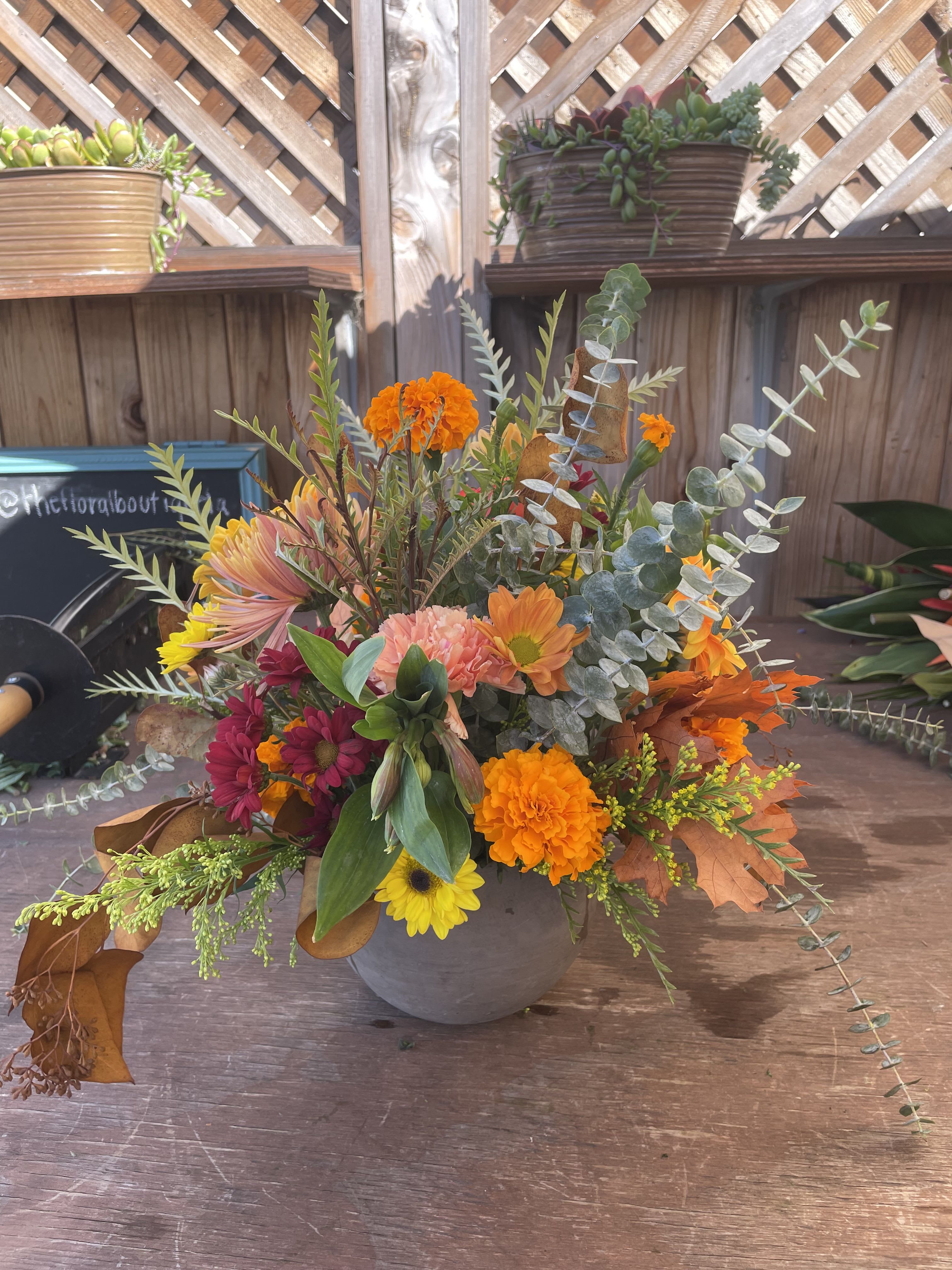 Franz - A ceramic pot filled with in season fall blooms that include maple leafs, fresh greenery, chrysanthemums and much more.