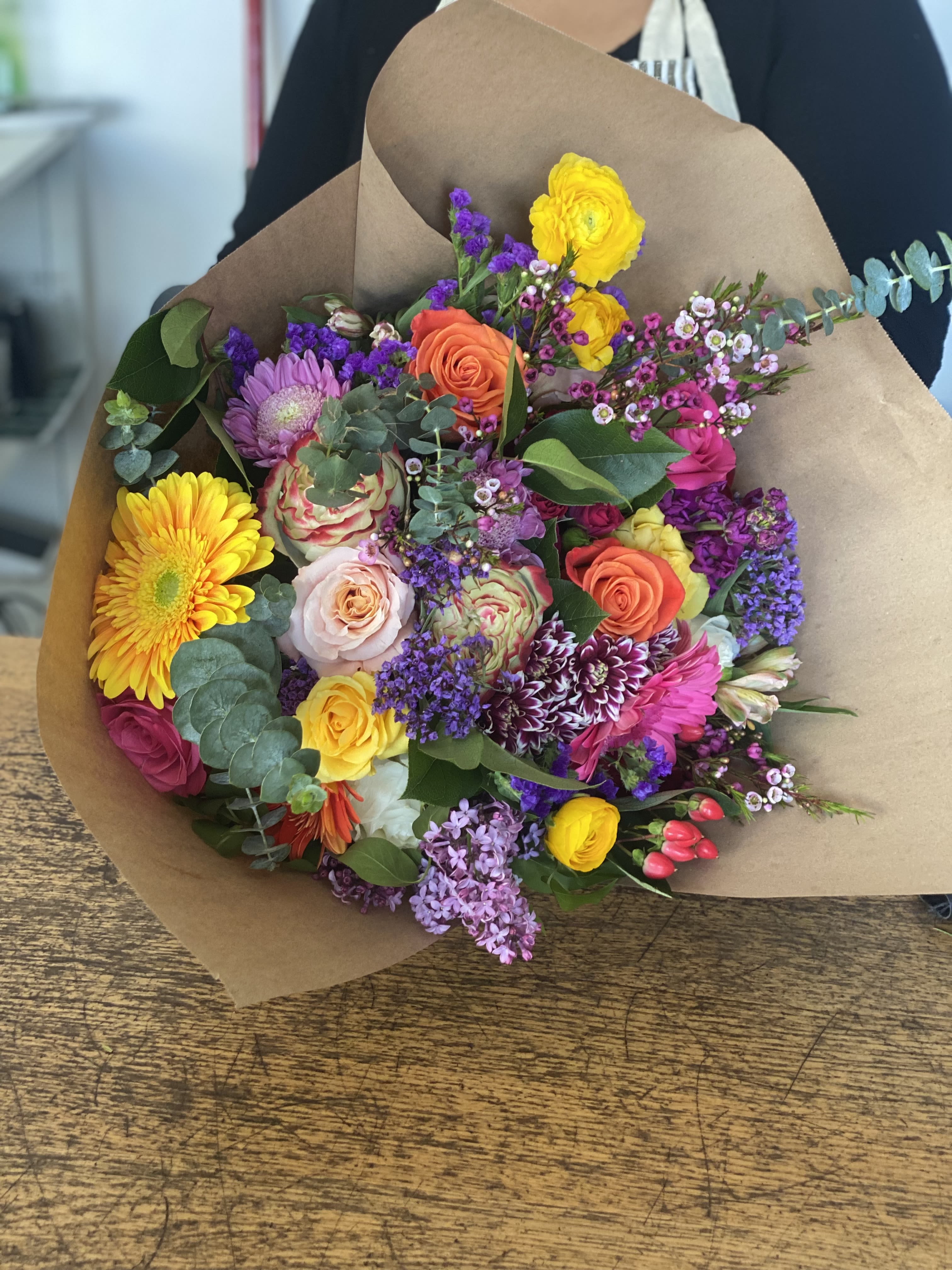 Mixed bouquet of colorful flowers wrapped in brown paper