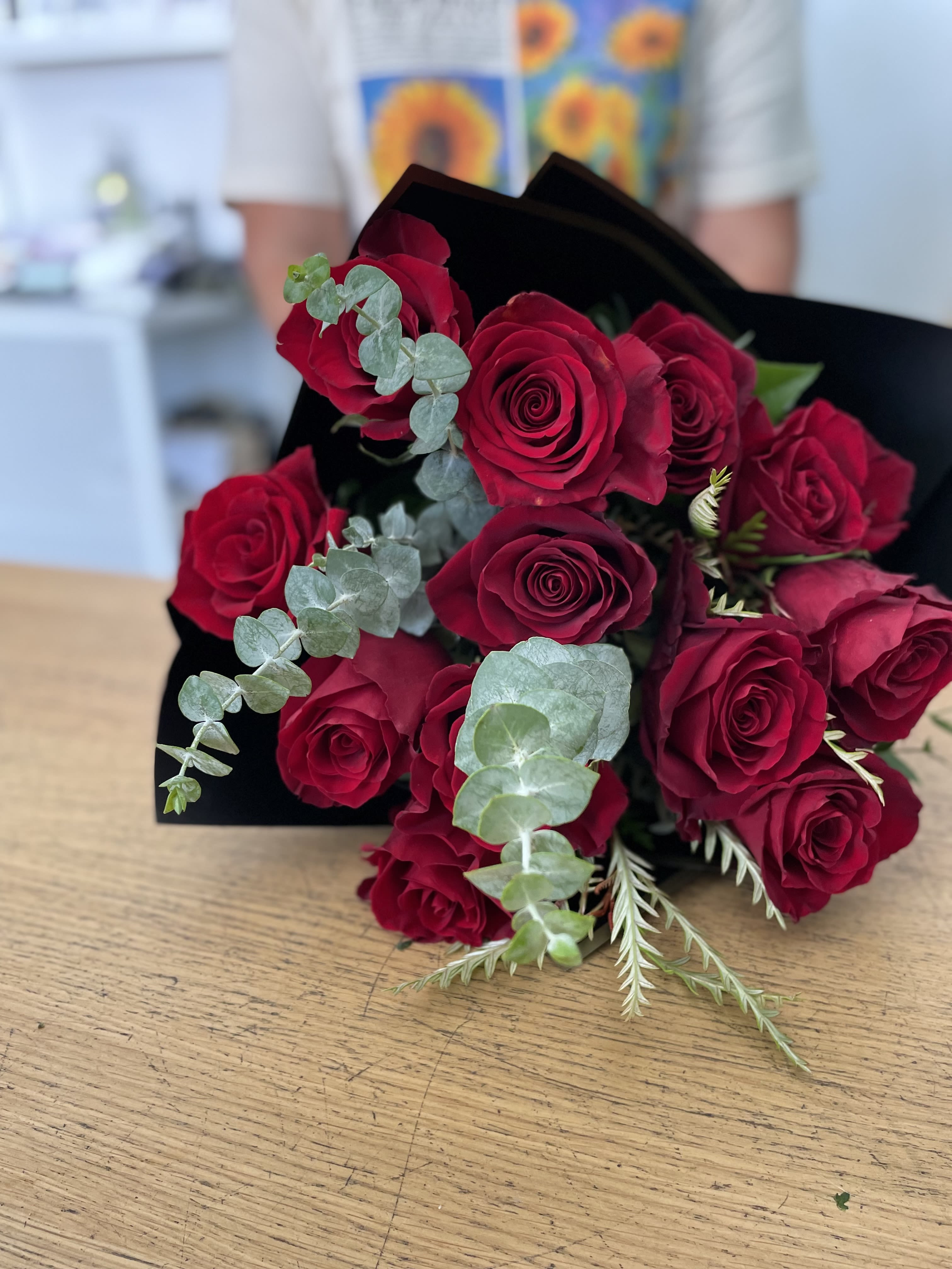 Bouquet of red roses with eucalyptus wrapped in black paper