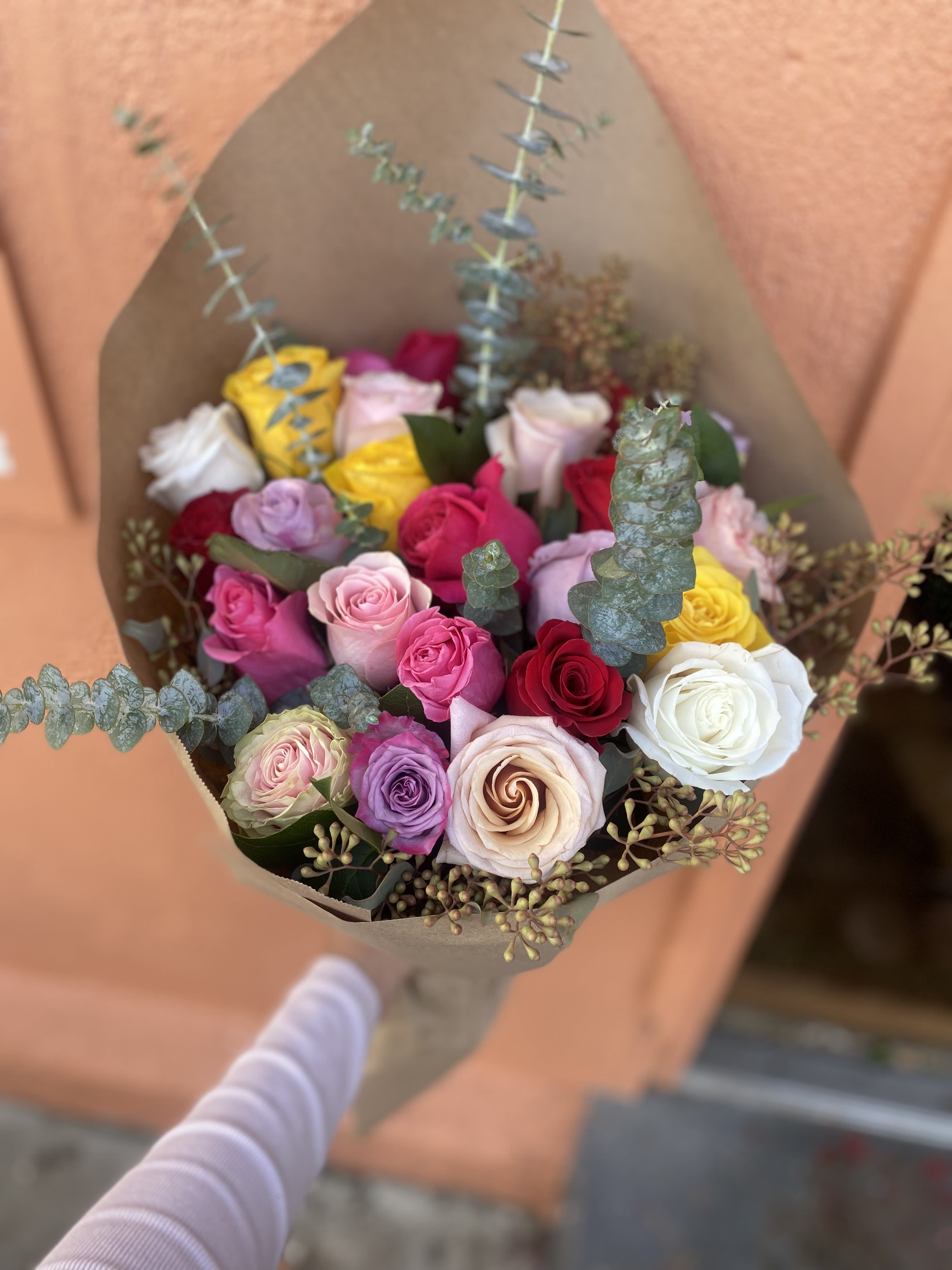 Bouquet of multicolored roses wrapped in brown paper