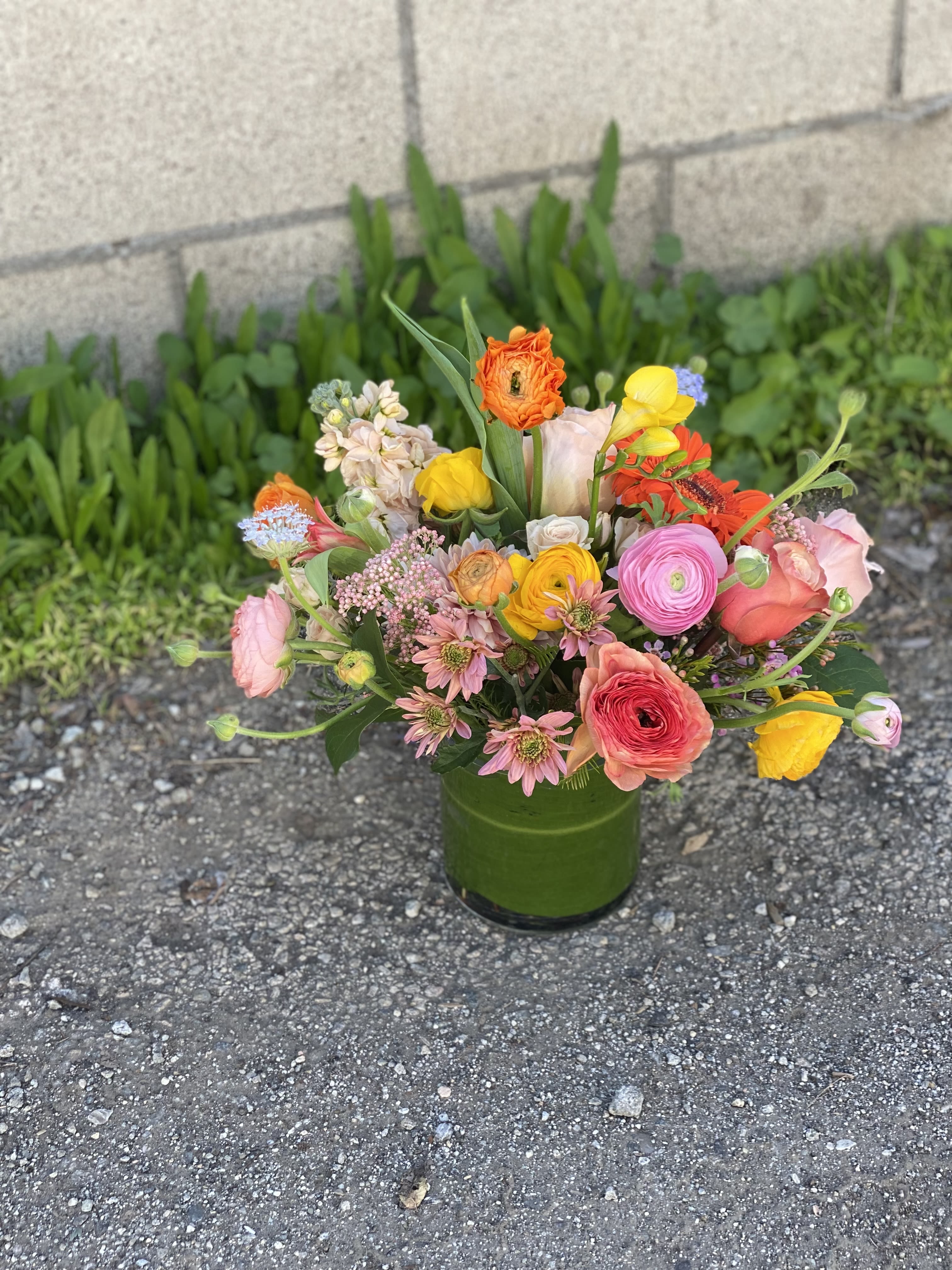 Mixed bouquet in a green vase with pink, yellow, orange, and white blooms