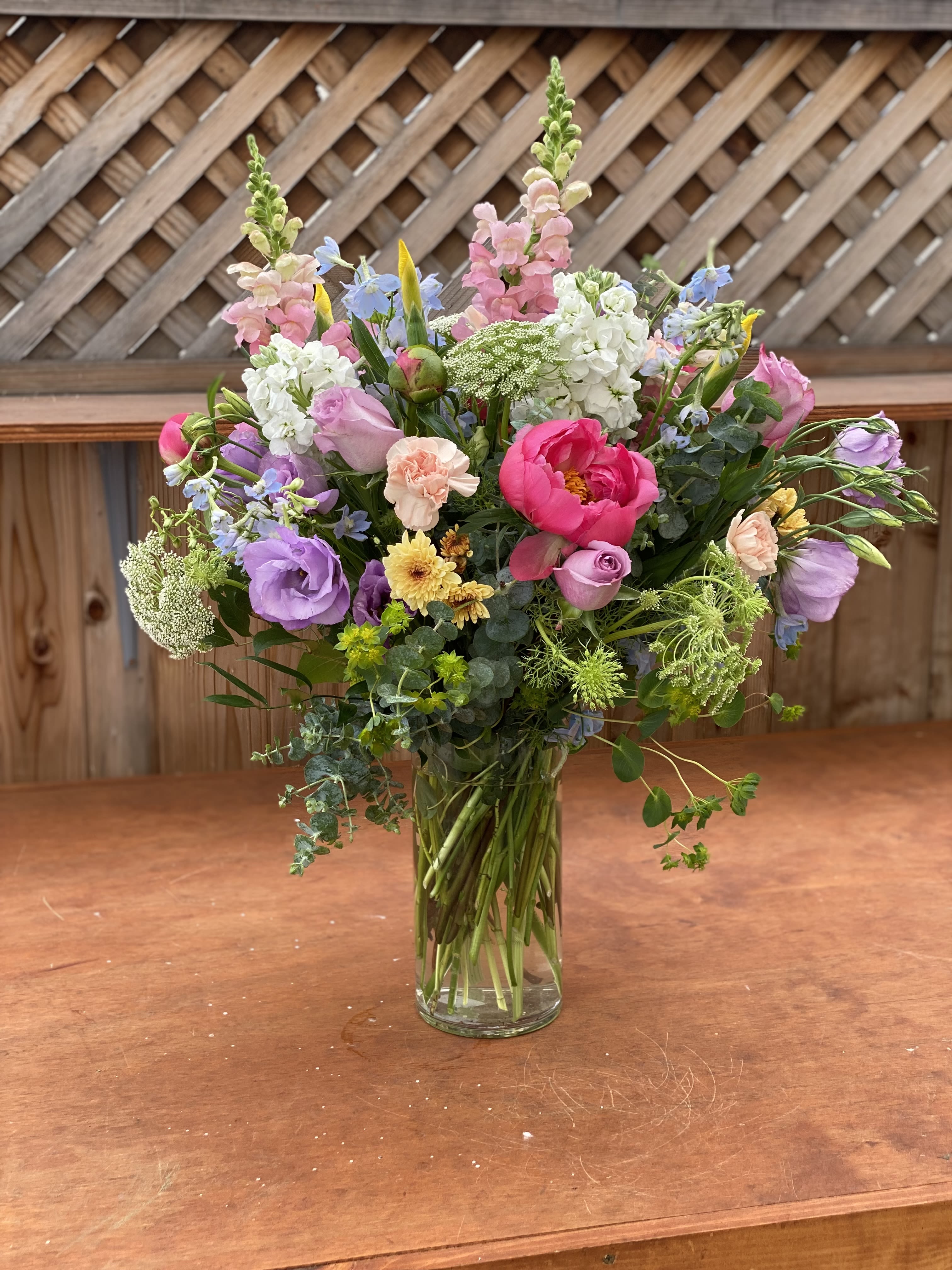 Mixed bouquet of pink, purple, white, and yellow flowers in a clear glass vase