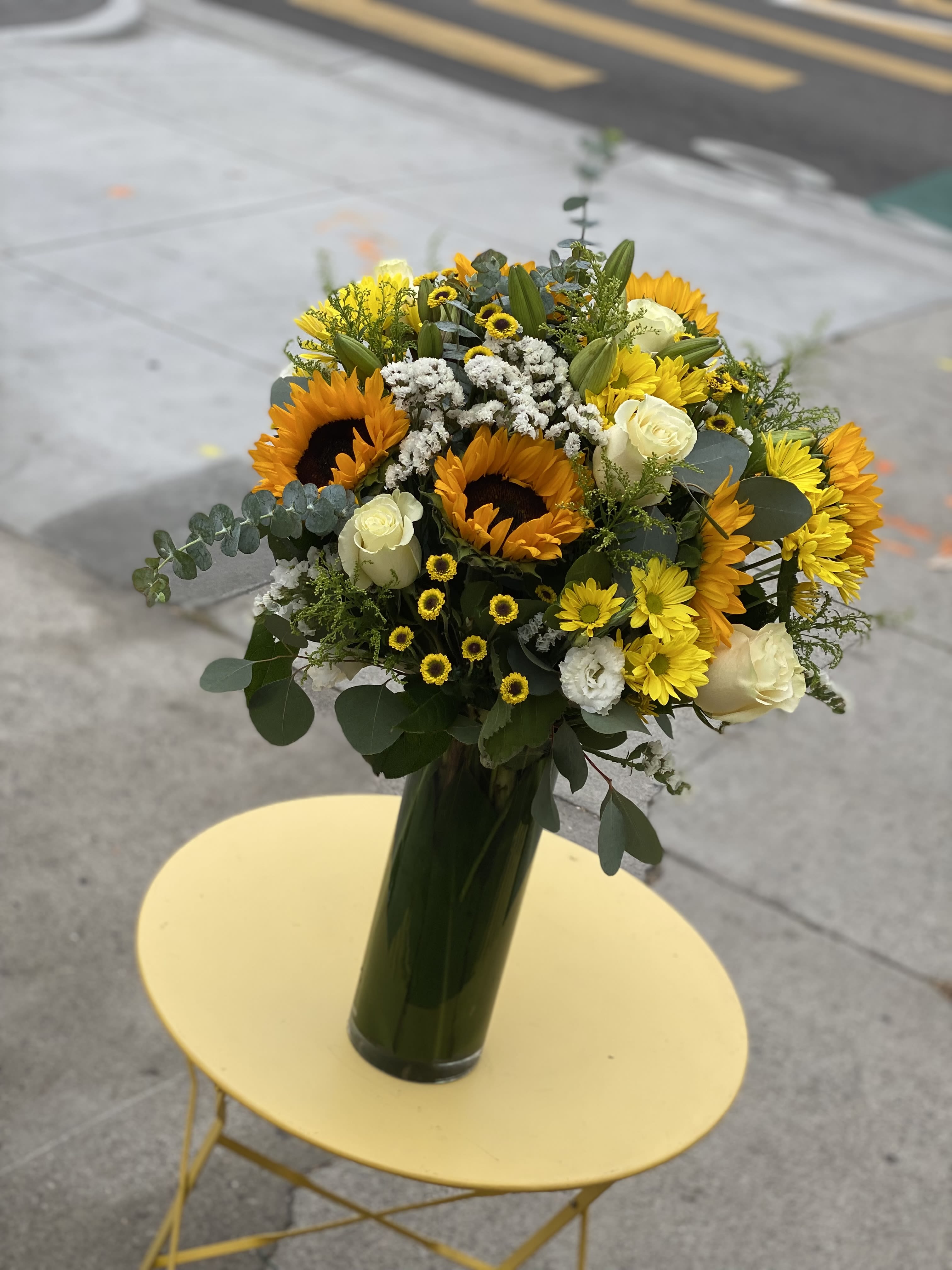 Yellow blossoms  - Share a smile with this lovely floral arrangement that includes sunflowers, roses, daisies, and more, all arranged in a glass vase