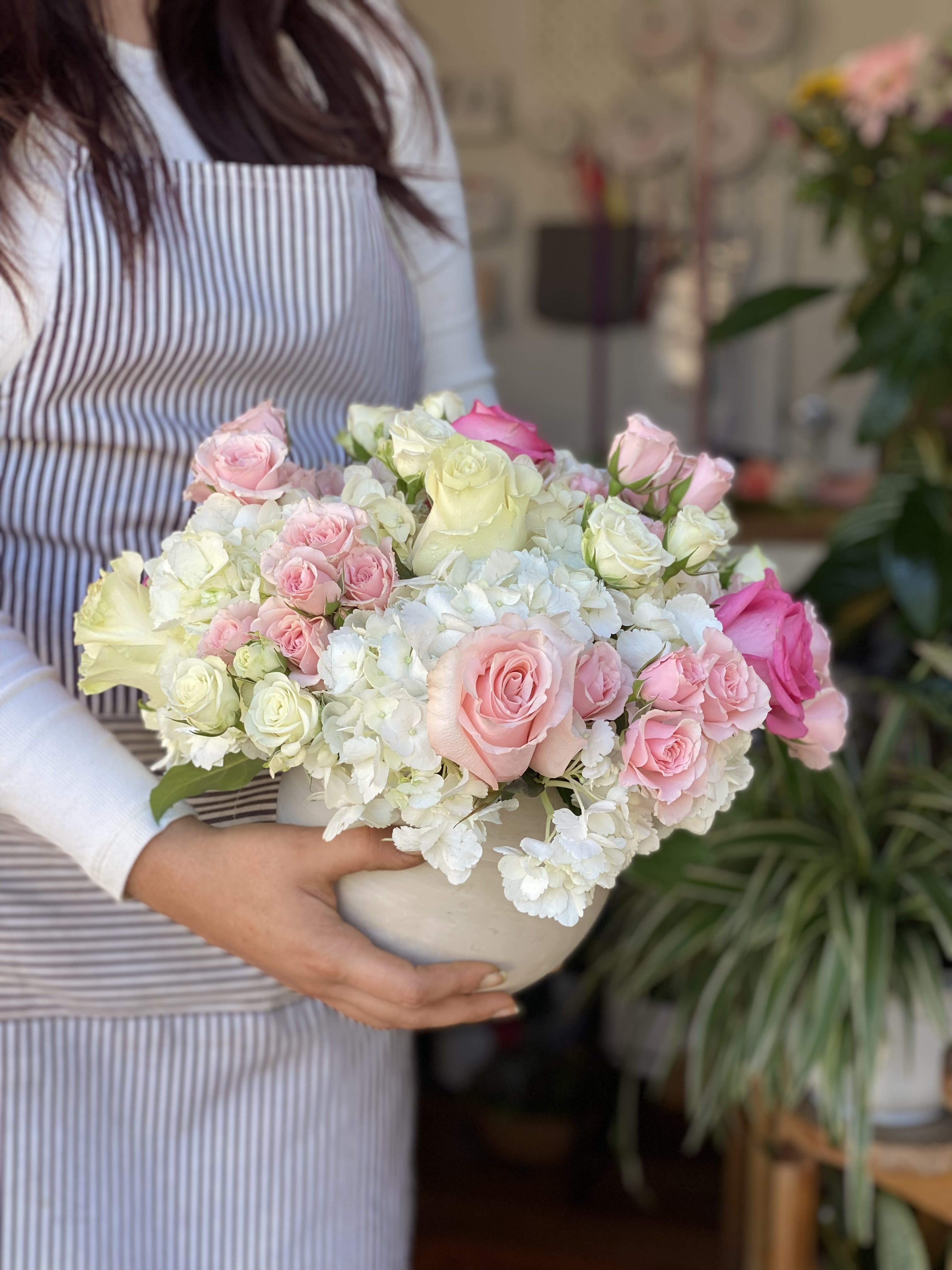 Pink and white roses arranged in a white bowl vase