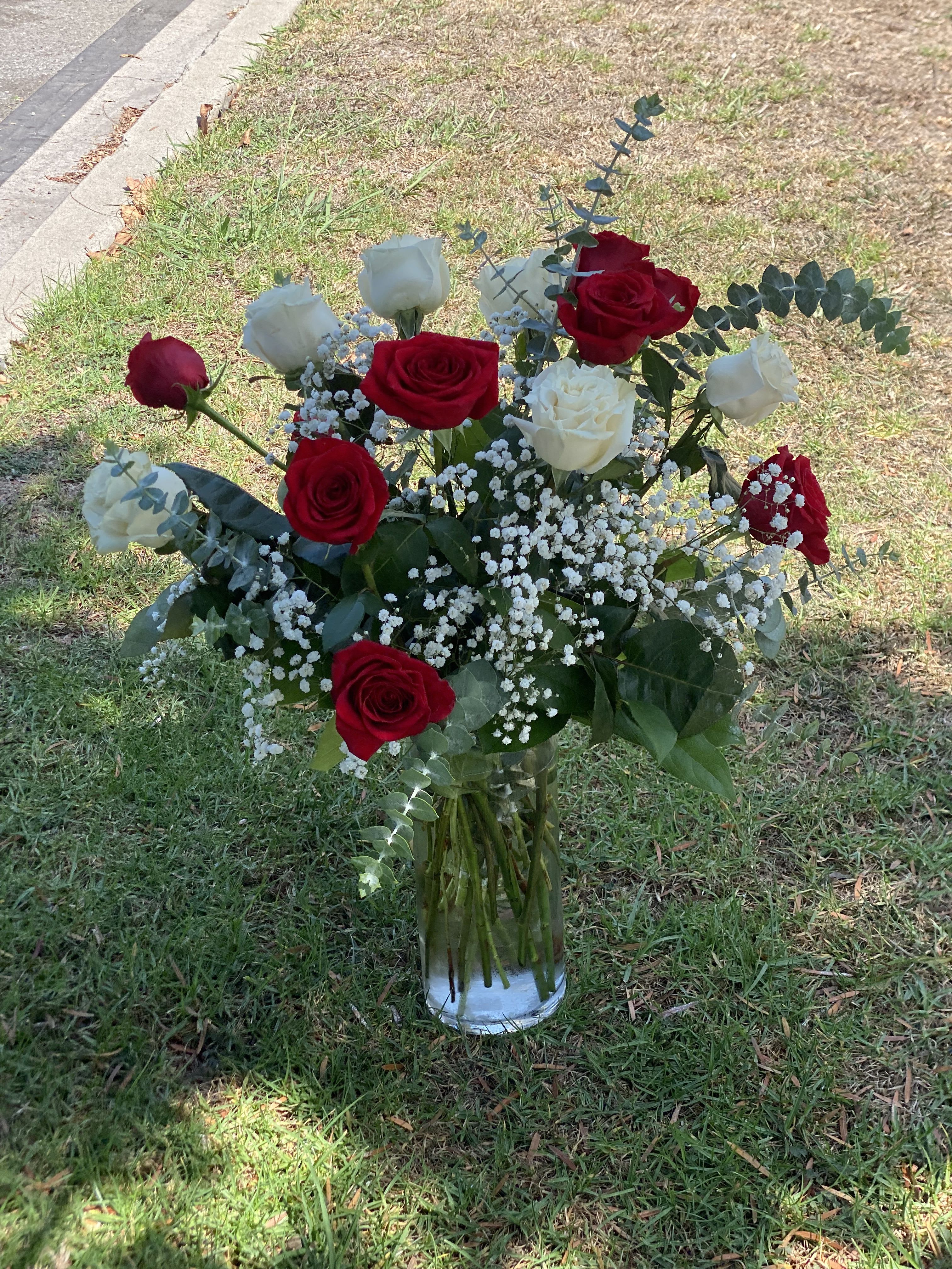 Red and white roses in a clear glass vase with baby's breath
