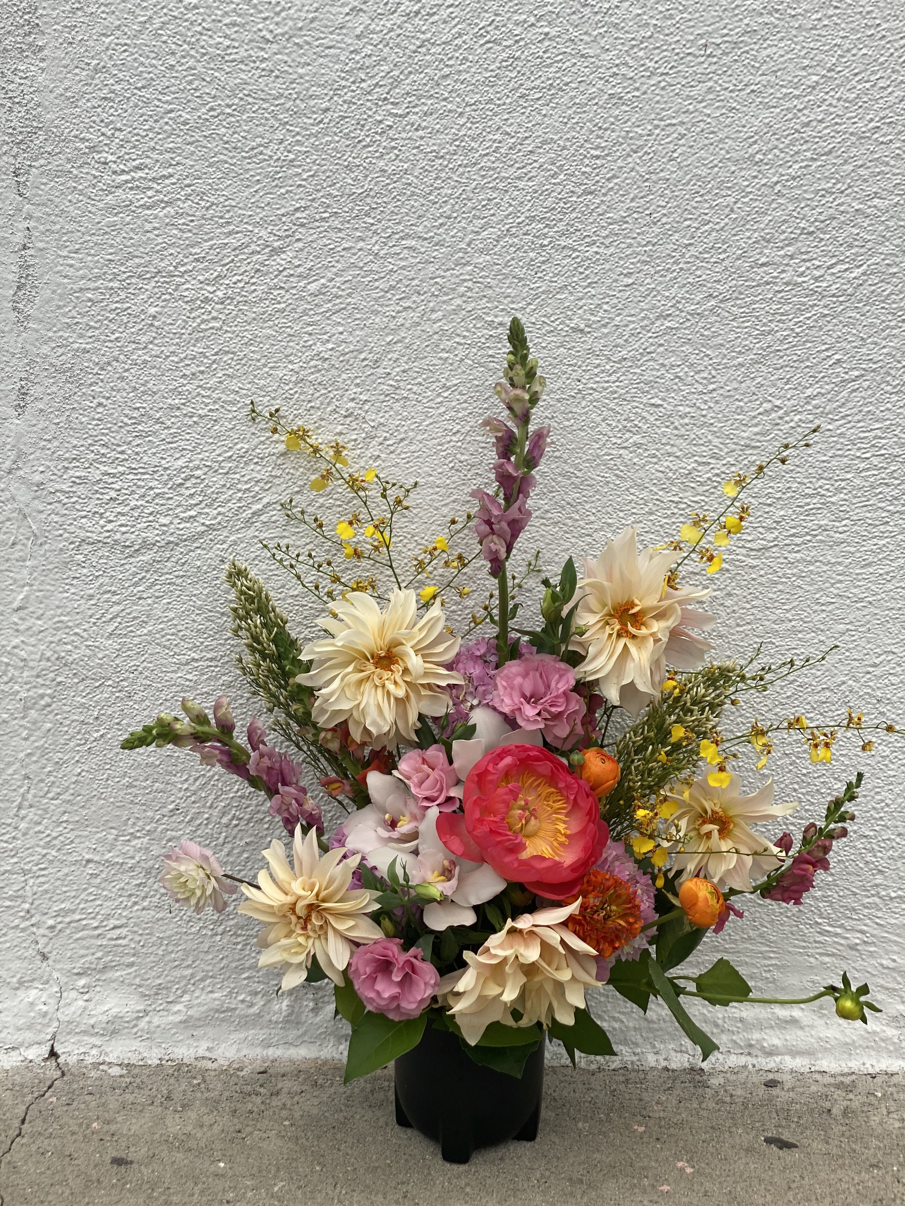 City babe - A unique arrangement in black vase, with dahlias, orchids, snap dragons and more in season blooms