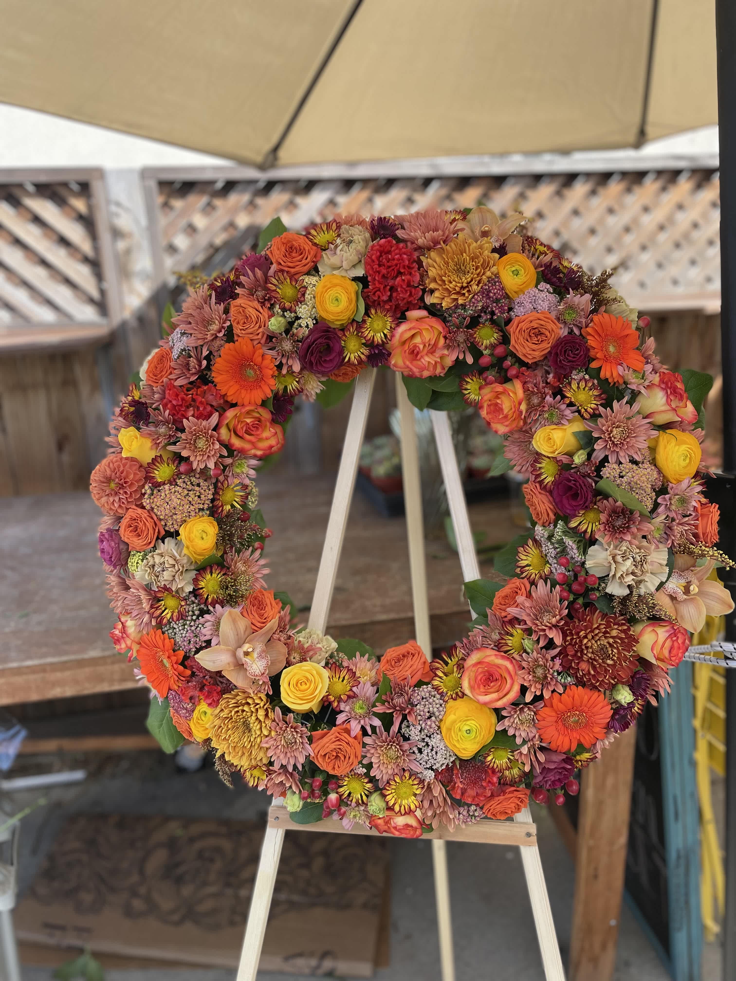 Circular floral wreath on an easel with orange, pink, yellow, and purple blooms