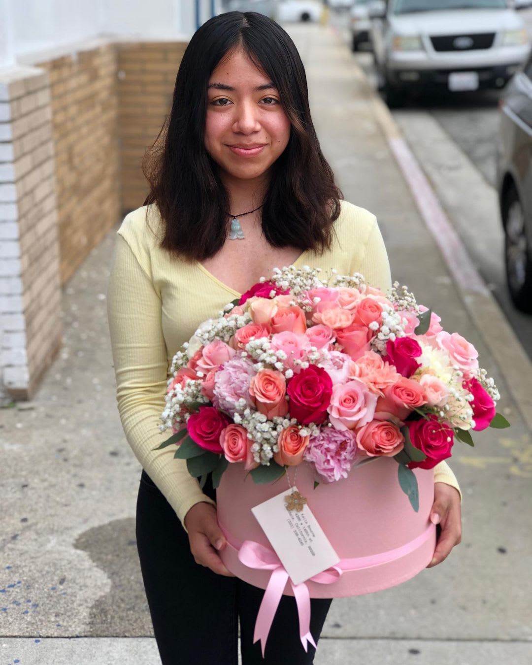 Woman holding a large pink box of mixed roses