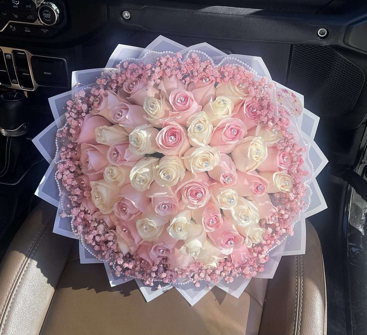Round bouquet of pink and white roses with pink filler flowers