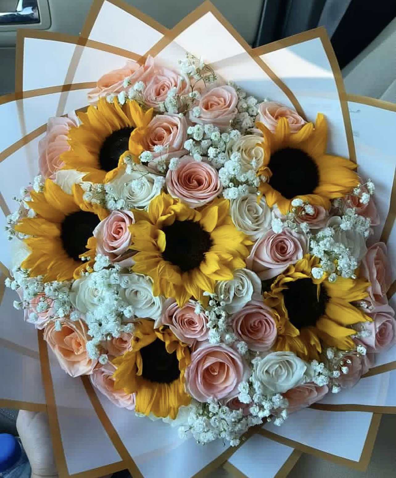 Bouquet of sunflowers and pastel roses wrapped in white paper