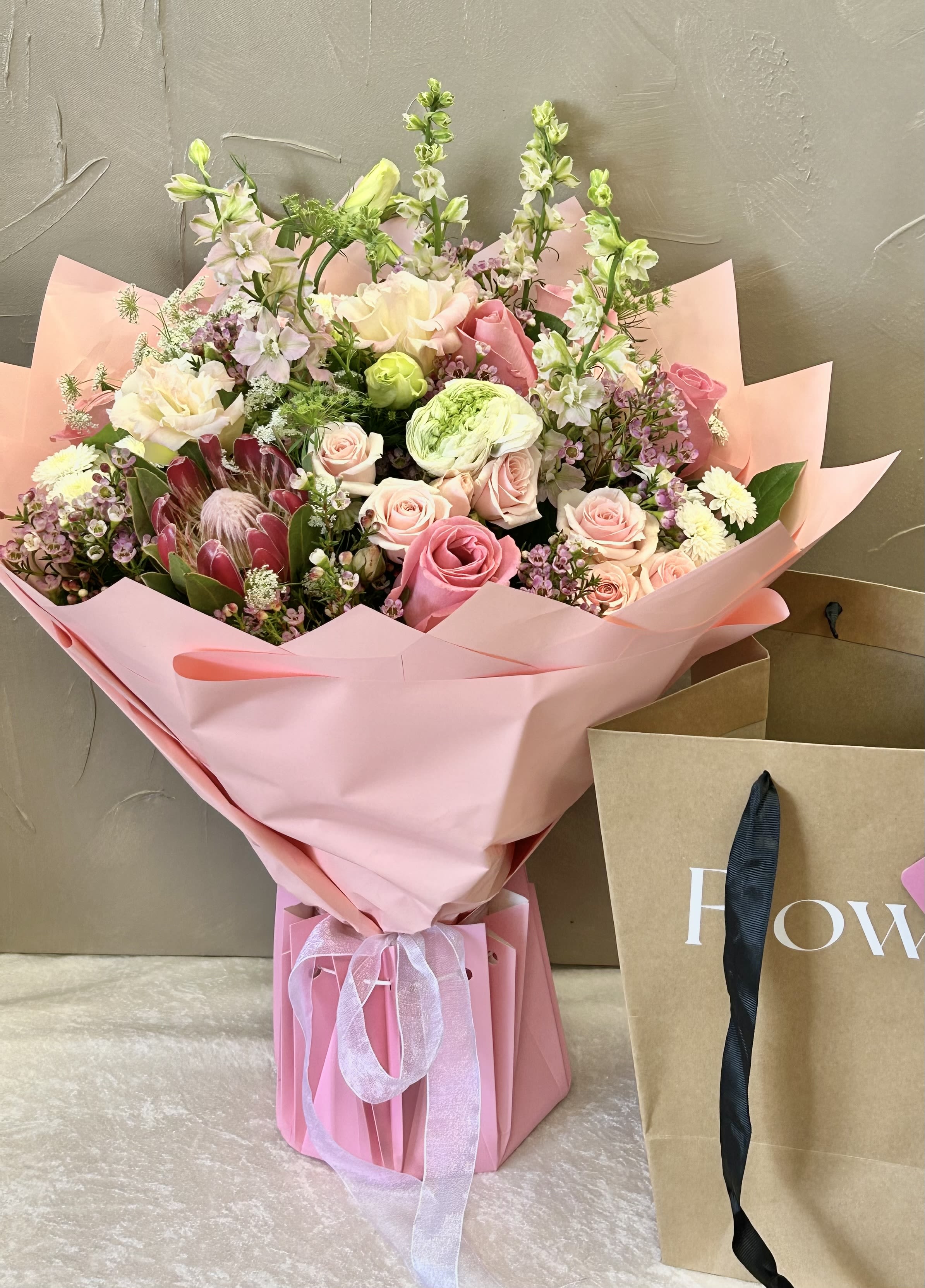Pink bouquet with roses and mixed blooms wrapped in pink paper