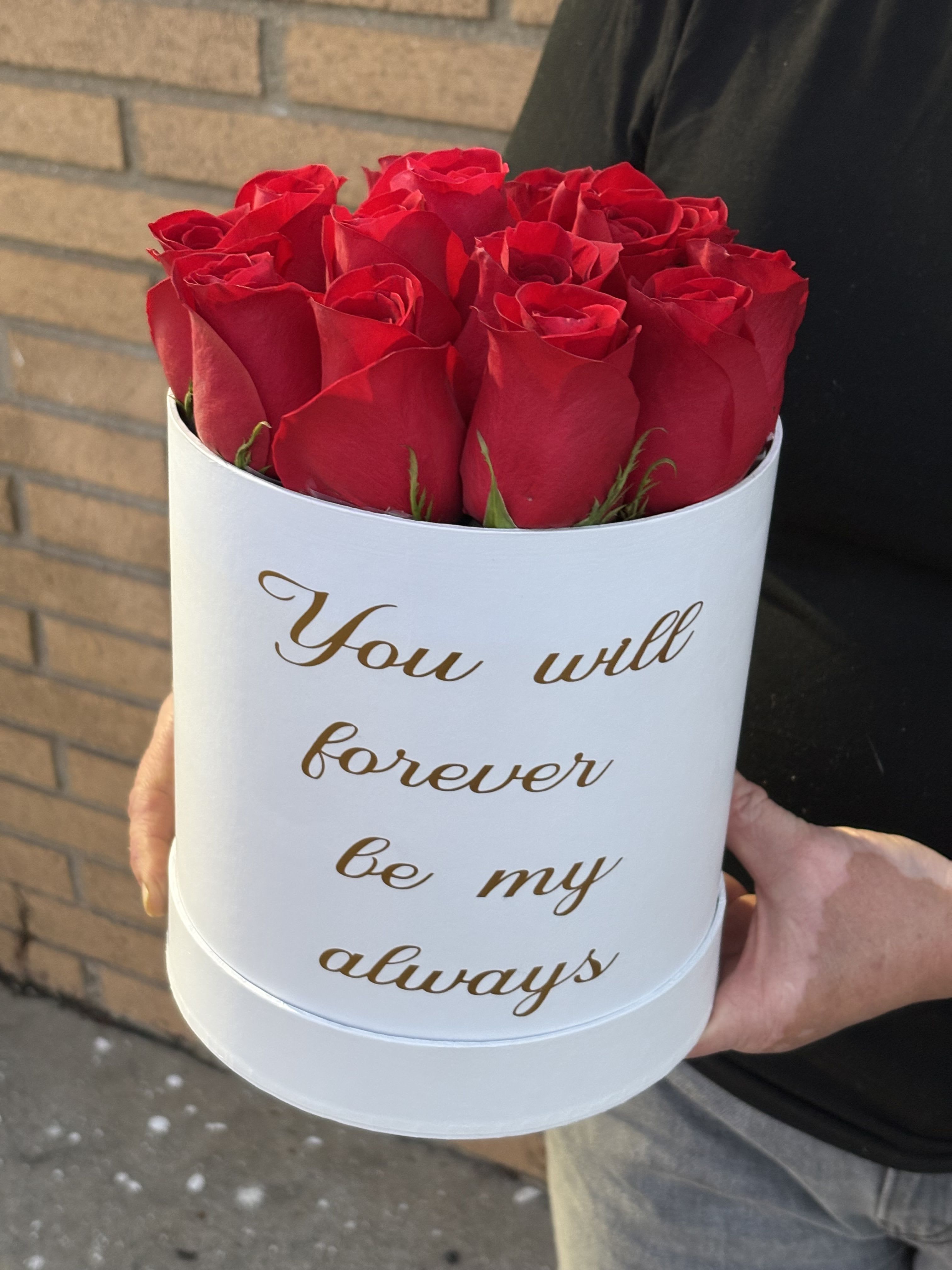 Red roses in a white round box with gold text