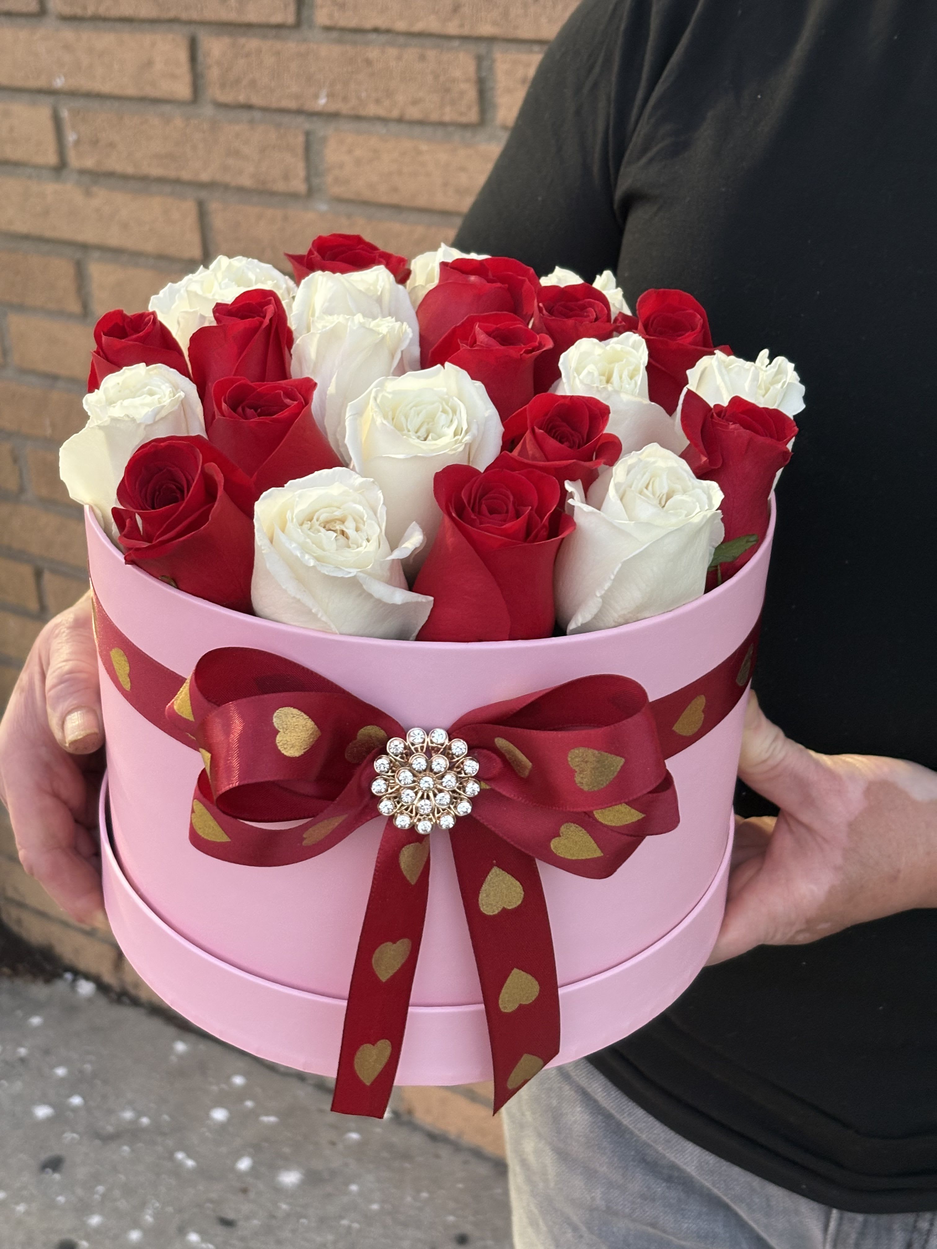 Red and white roses in a pink round box with a heart ribbon