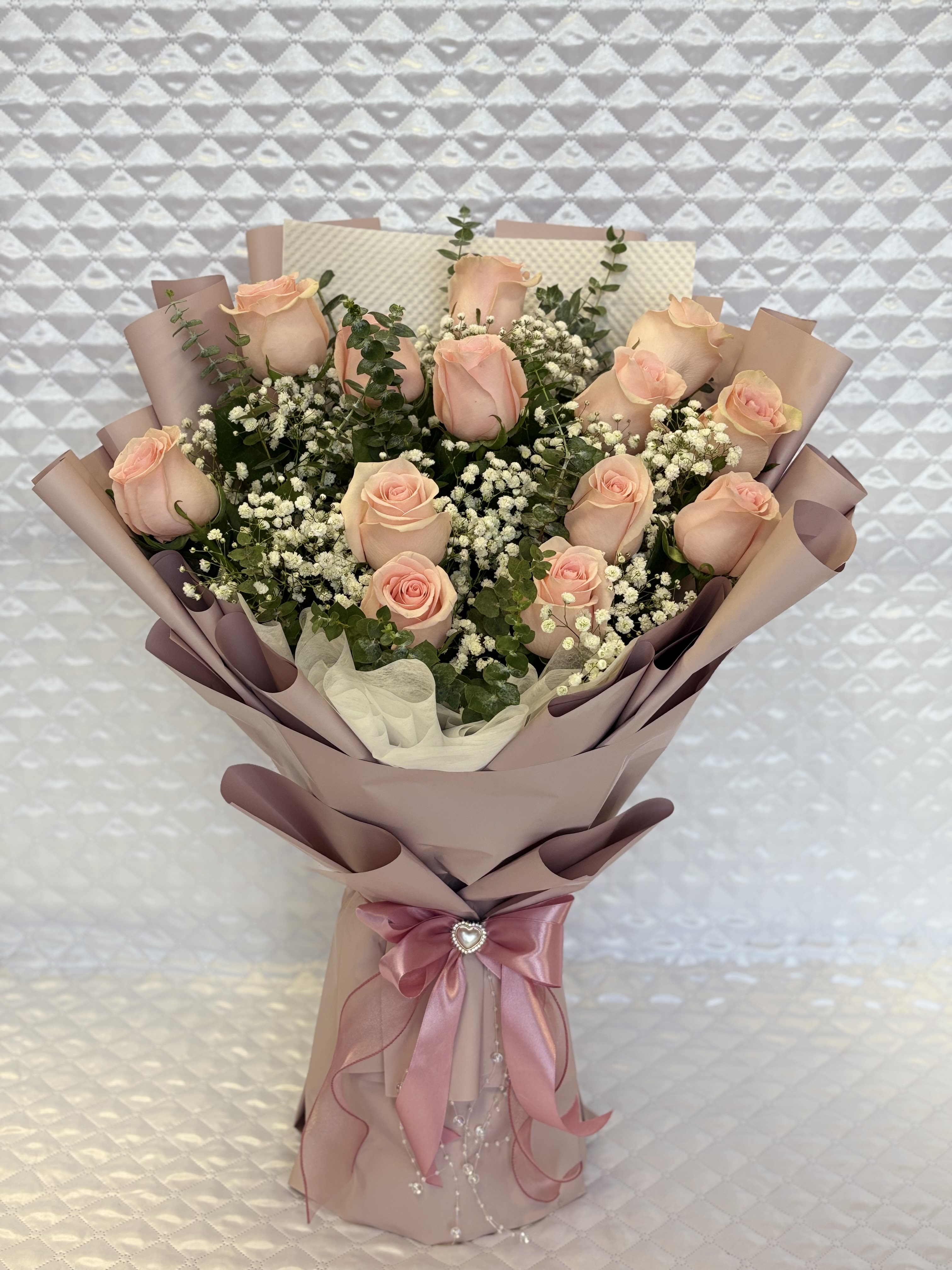 Bouquet of pale pink roses with baby's breath in mauve wrapping