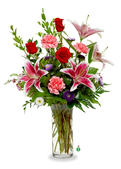 Tall glass vase of red roses, pink lilies and carnations with purple accent flowers