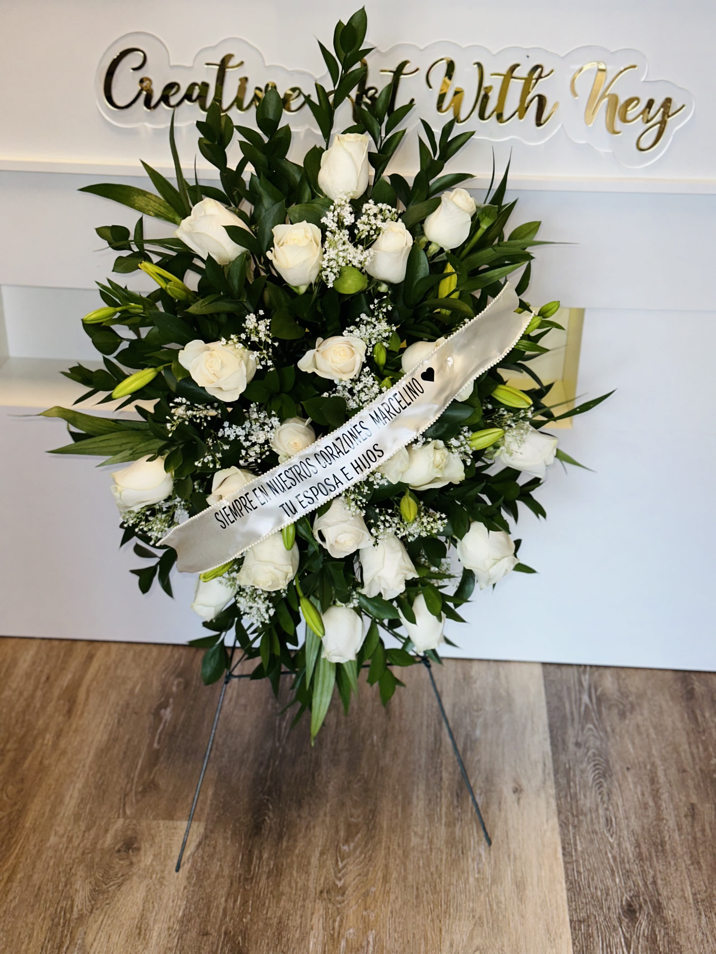 White rose standing spray with a condolence ribbon on an easel