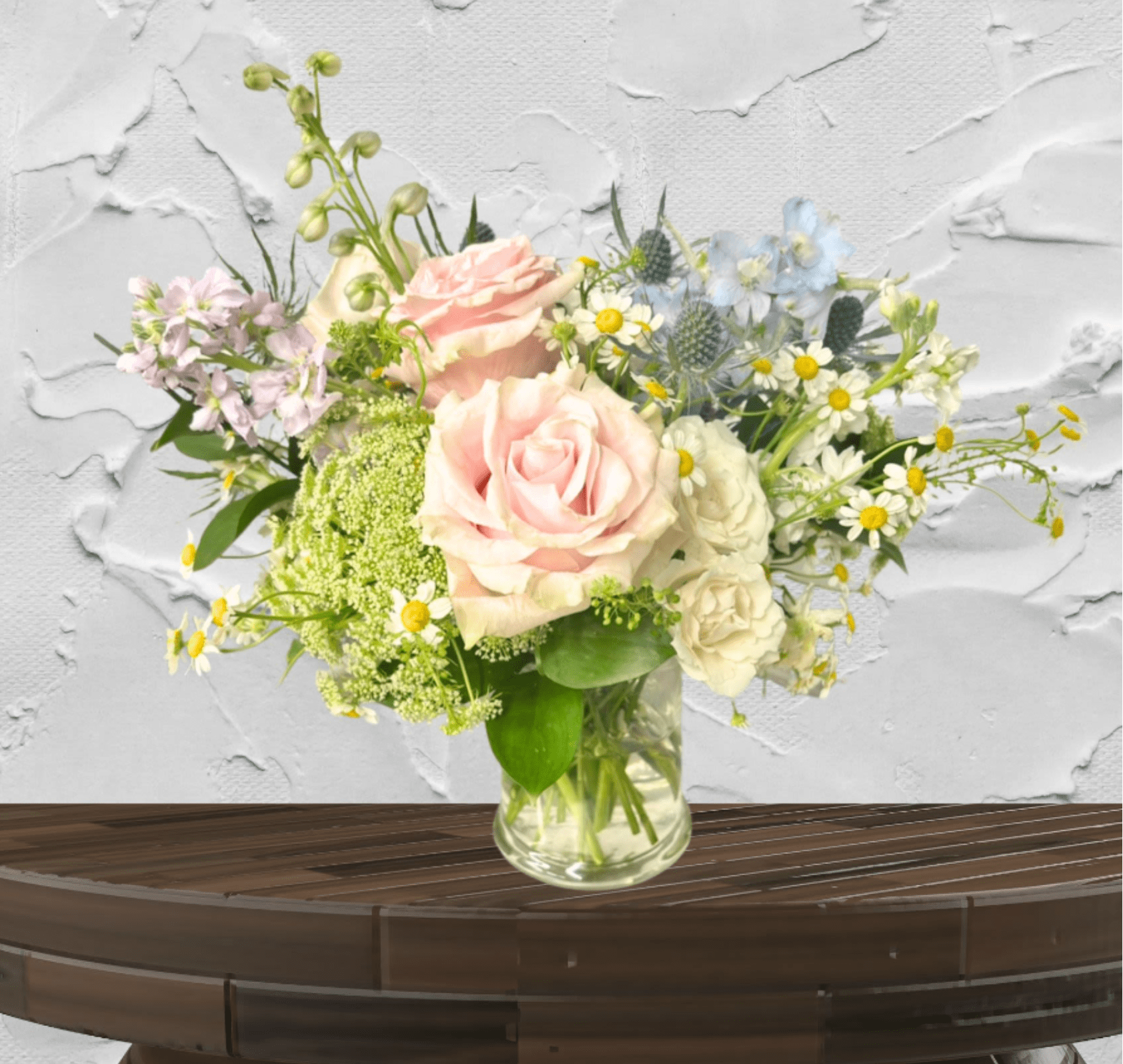 Blush Lyric - "Hand-crafted by accredited Master Florist Tricia Won (AIFD, EMC, IMF) using premium seasonal market blooms. No two arrangements are identical."  The Blush Lyric is a masterclass in "Petite Luxe" design, proving that a smaller footprint can still command a room. This arrangement is a sophisticated study in soft, airy color theory, featuring a dreamlike palette of blush pink, cream, and sky blue. It is designed for the modern connoisseur who appreciates intricate textures and a calm, artistic aesthetic.  This custom weekly arrangement features a multi-dimensional silhouette that encourages the eye to wander through layers of soft blooms and seasonal textures. Our designers choose the most premium blooms available in this soft dreamy color palette and choose blooms based on seasonality and availability.