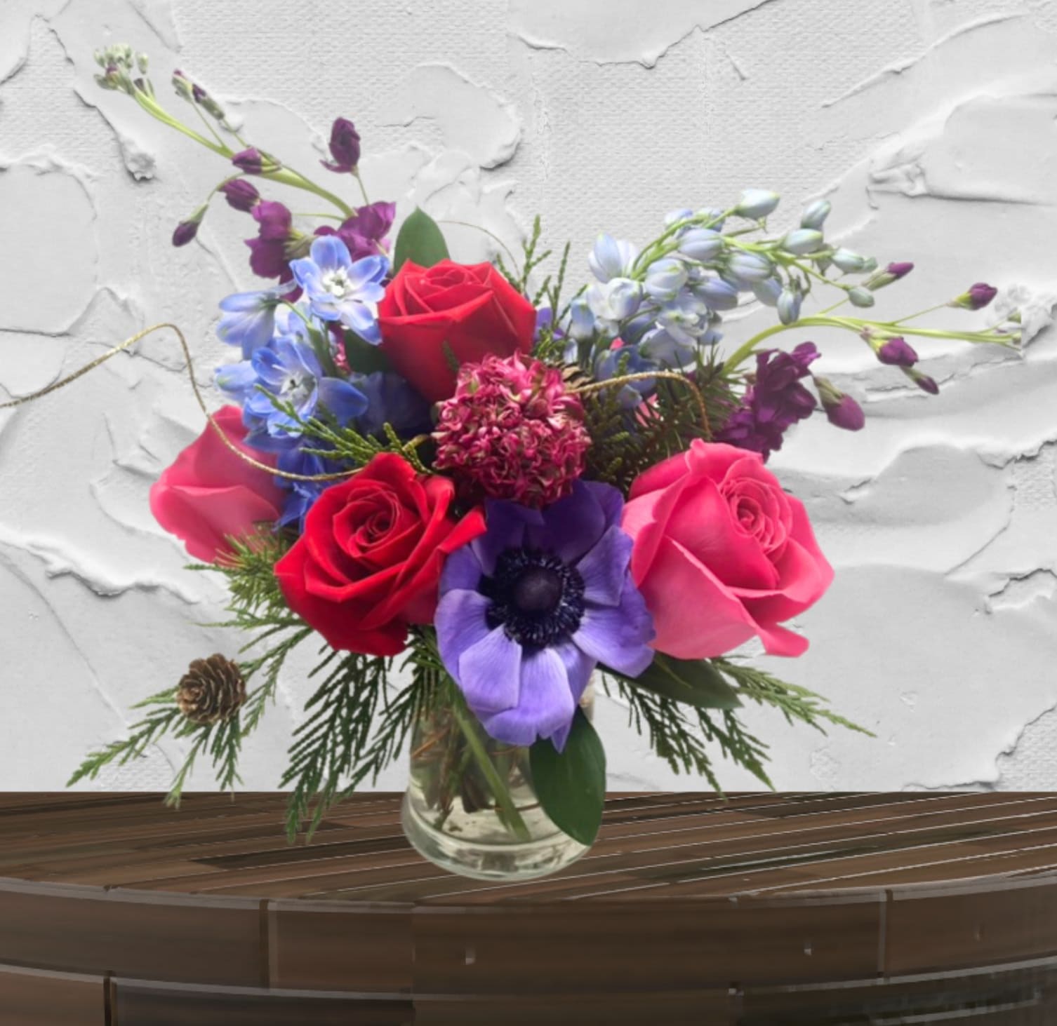 Crimson Lyric - "Hand-crafted by accredited Master Florist Tricia Won (AIFD, EMC, IMF) using premium seasonal market blooms. No two arrangements are identical."  The Crimson Lyric Intimate Luxury. Spirited Color. Designer Detail.  The Crimson Lyric is a compact yet high-impact design that proves true luxury doesn't always require a large scale. This "Petite Luxe" arrangement is a vibrant concentrated burst of our signature romantic style, featuring a rich, spirited palette of deep reds, magentas, and electric blues. It is the perfect piece for adding a touch of designer flair to an intimate space.  The Design &amp; Florals Crafted with the same attention to detail as our larger masterpieces, this arrangement uses a variety of jewel toned premium stems to create a lush, multi-dimensional look.  This custom design features jewel toned florals that are chosen based on seasonality and availability. 