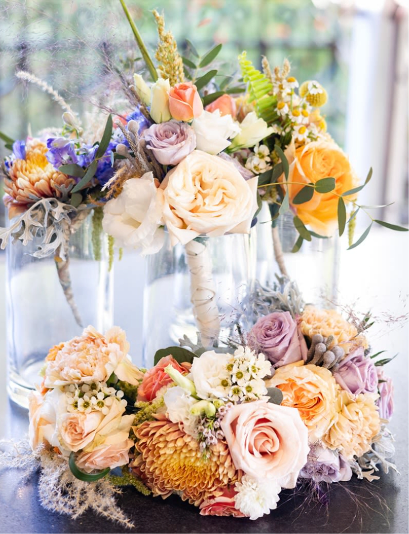 Pastel floral arrangements in clear glass vases with roses and mixed blooms