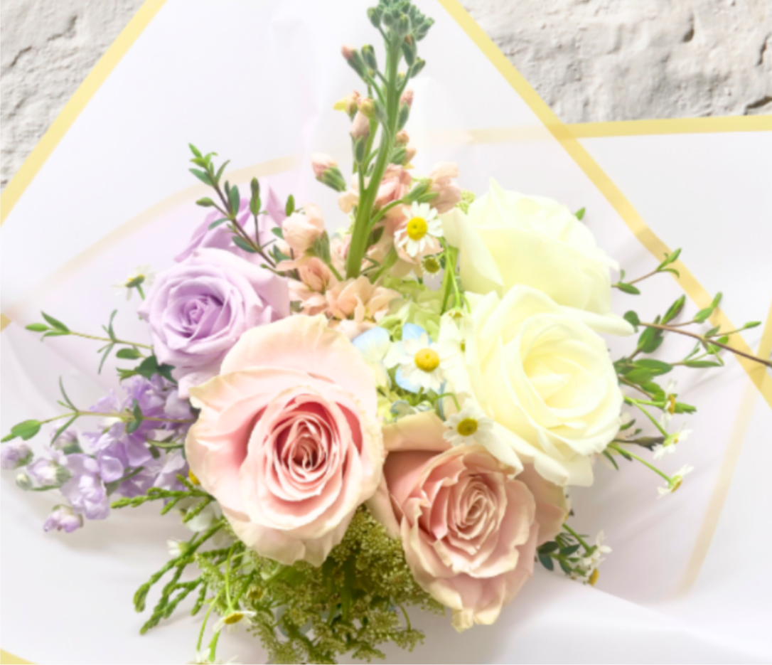 Bouquet of pastel roses and small daisies wrapped in white paper