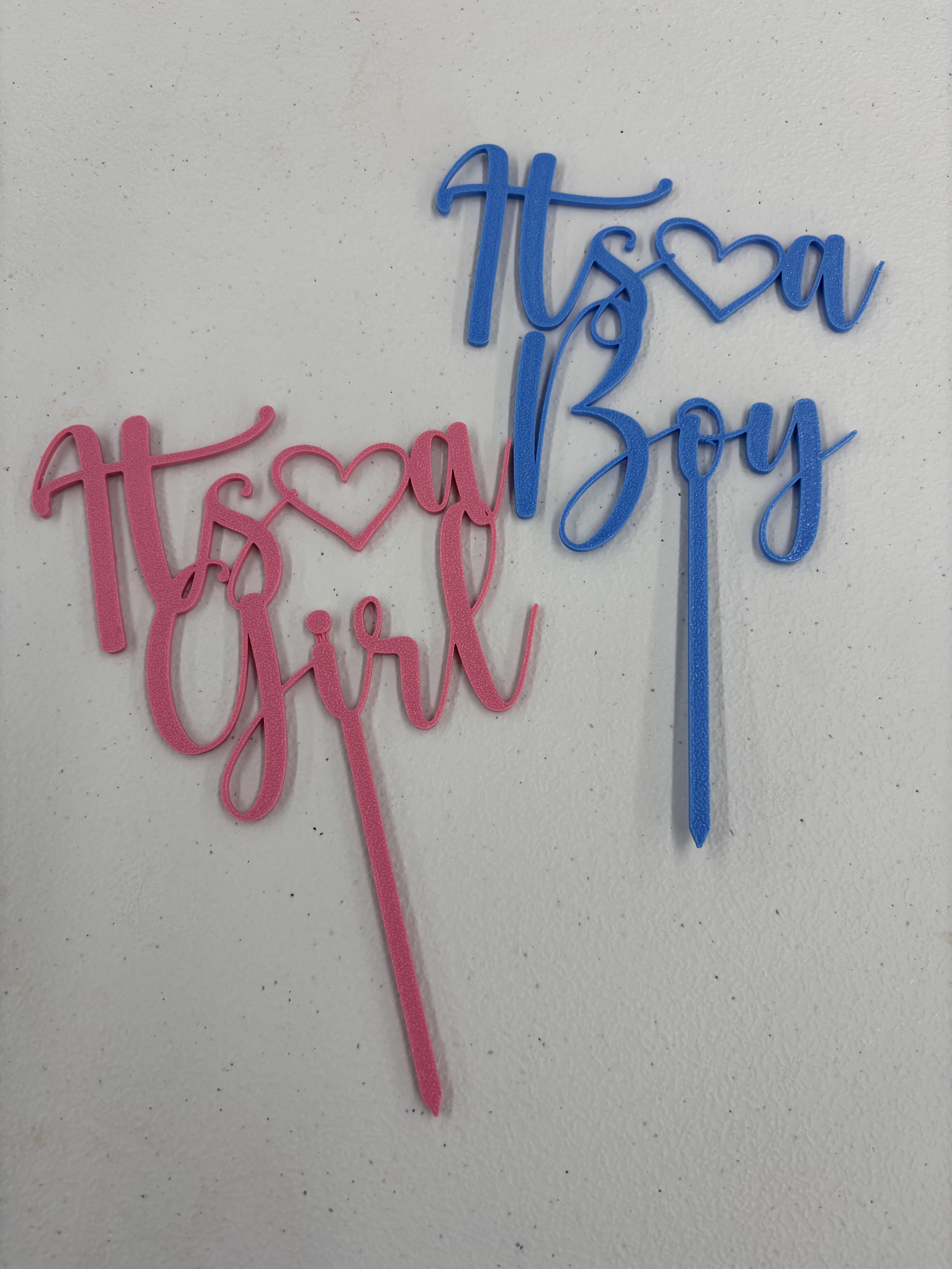 Pink and blue baby shower cake toppers reading "It's a Girl" and "It's a Boy"