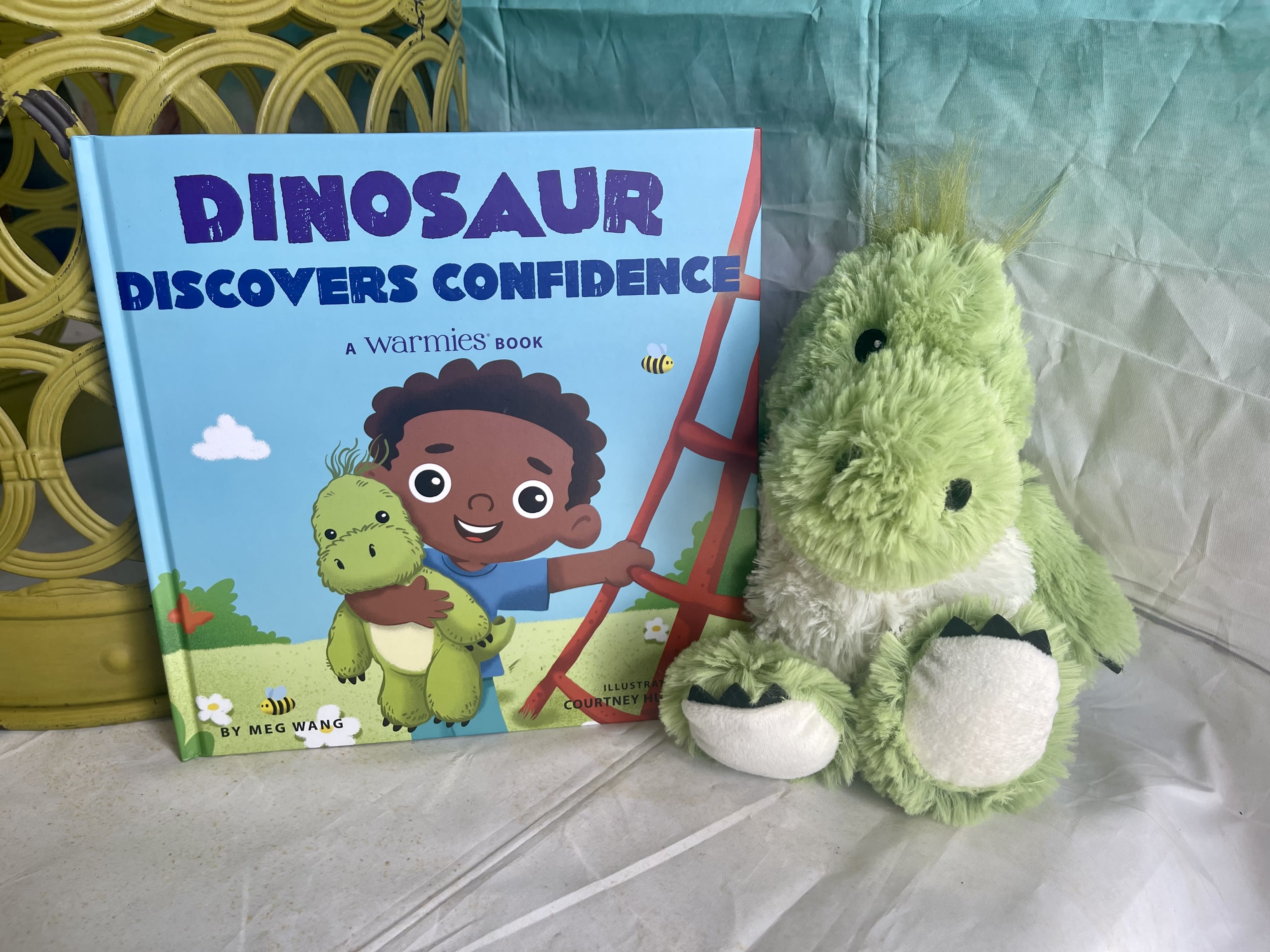 Children's dinosaur book beside a green plush dinosaur toy