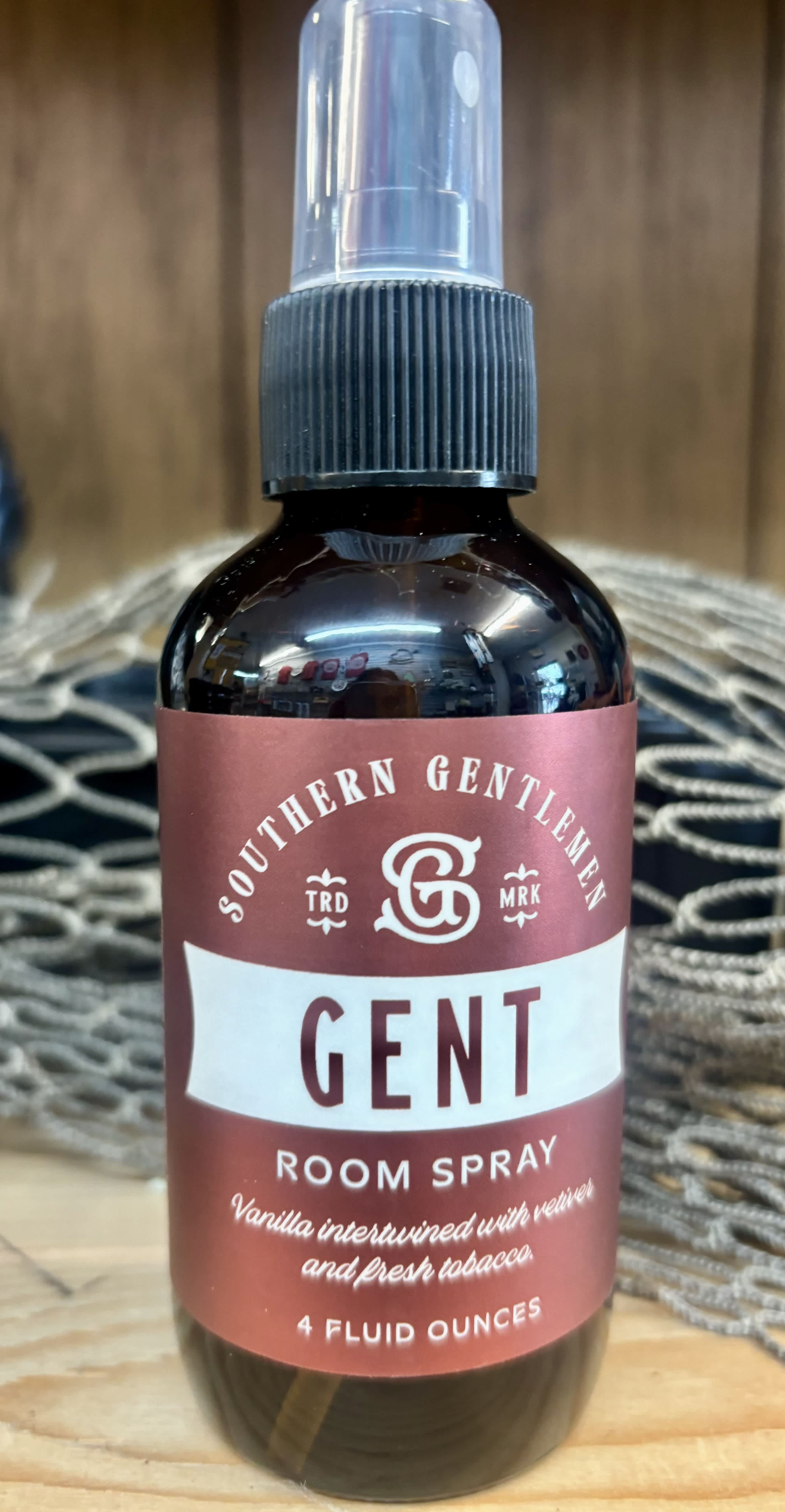 Brown room spray bottle with a clear cap and maroon label