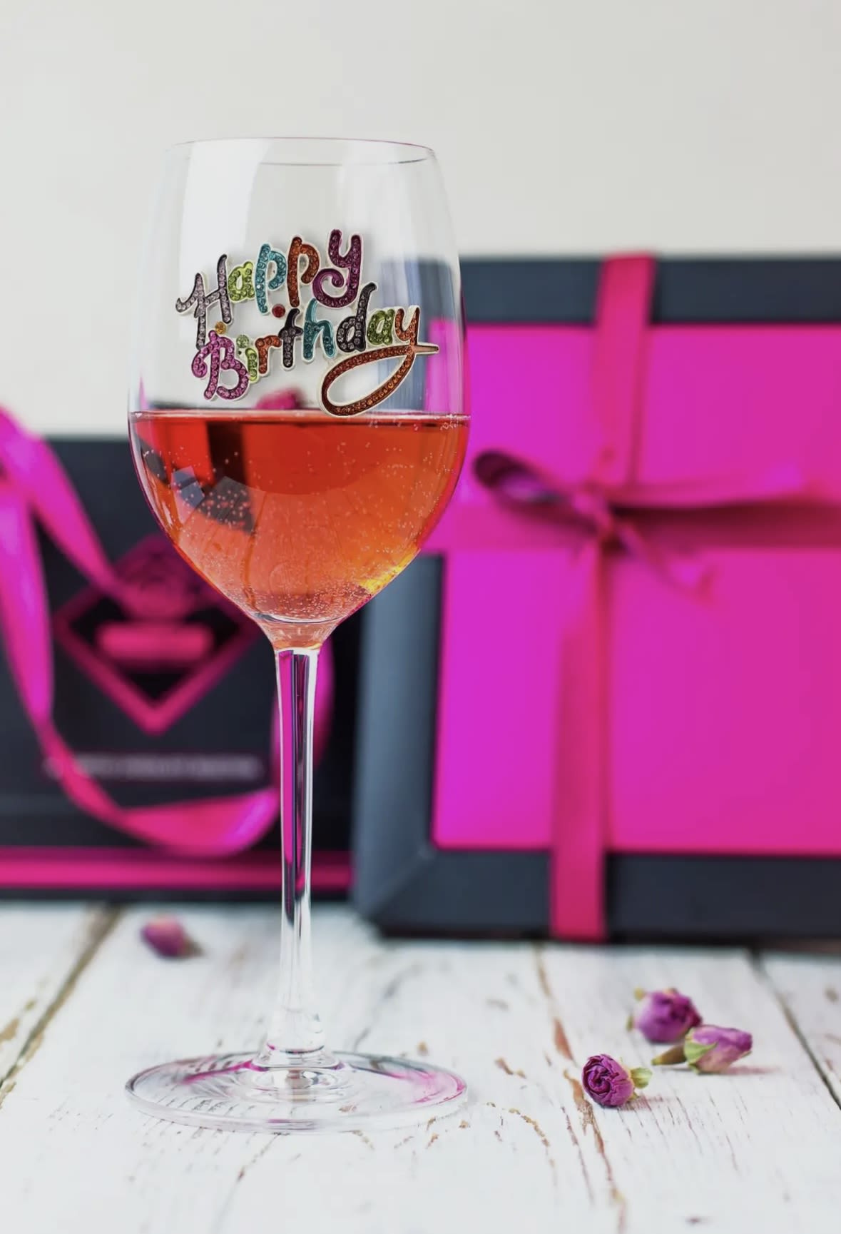 Wine glass with a colorful happy birthday decal, filled with pink drink