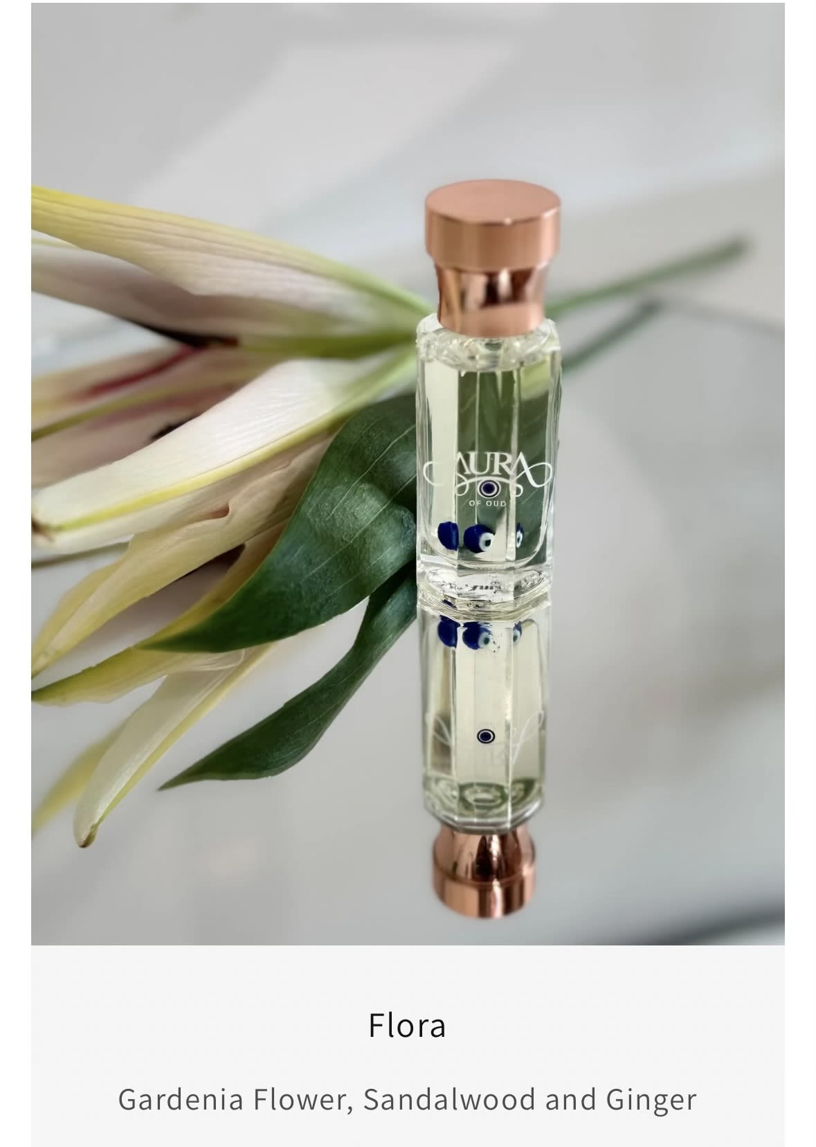 Perfume bottle beside a white flower and green leaves