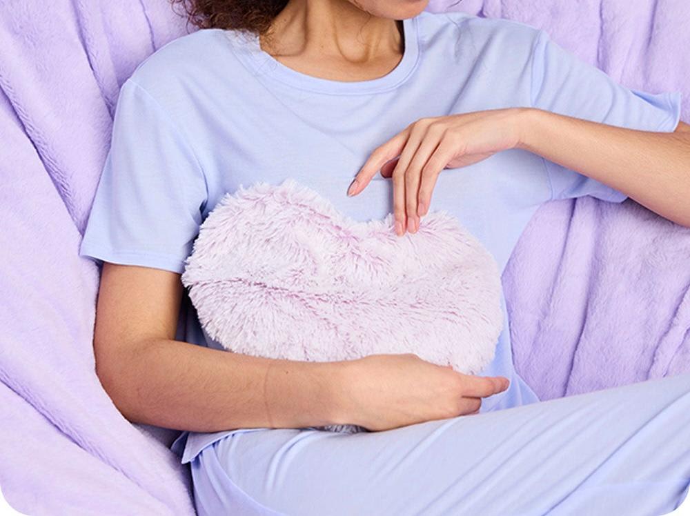 Person holding a fluffy heart-shaped plush pillow