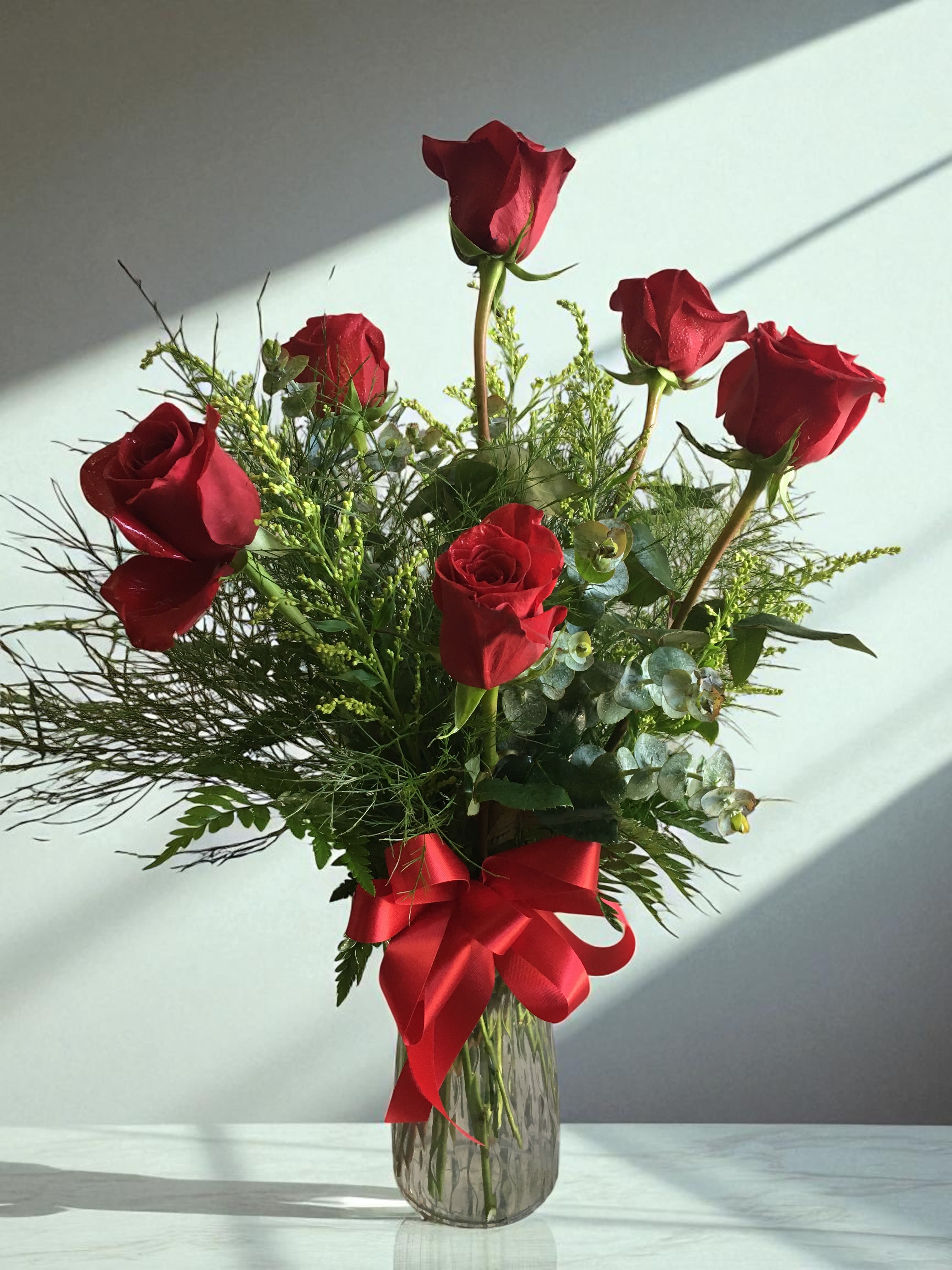 Yours Truly (Also available in other colors- specify color in special instructions) - 6 Red roses traditionally designed in a glass vase with filler and greens. Color of bow and filler will vary.