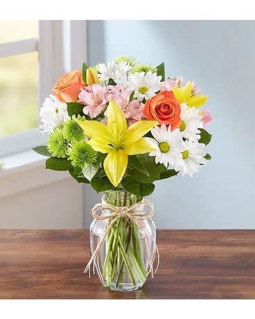 Mixed bouquet of lilies, roses, and daisies in a glass vase