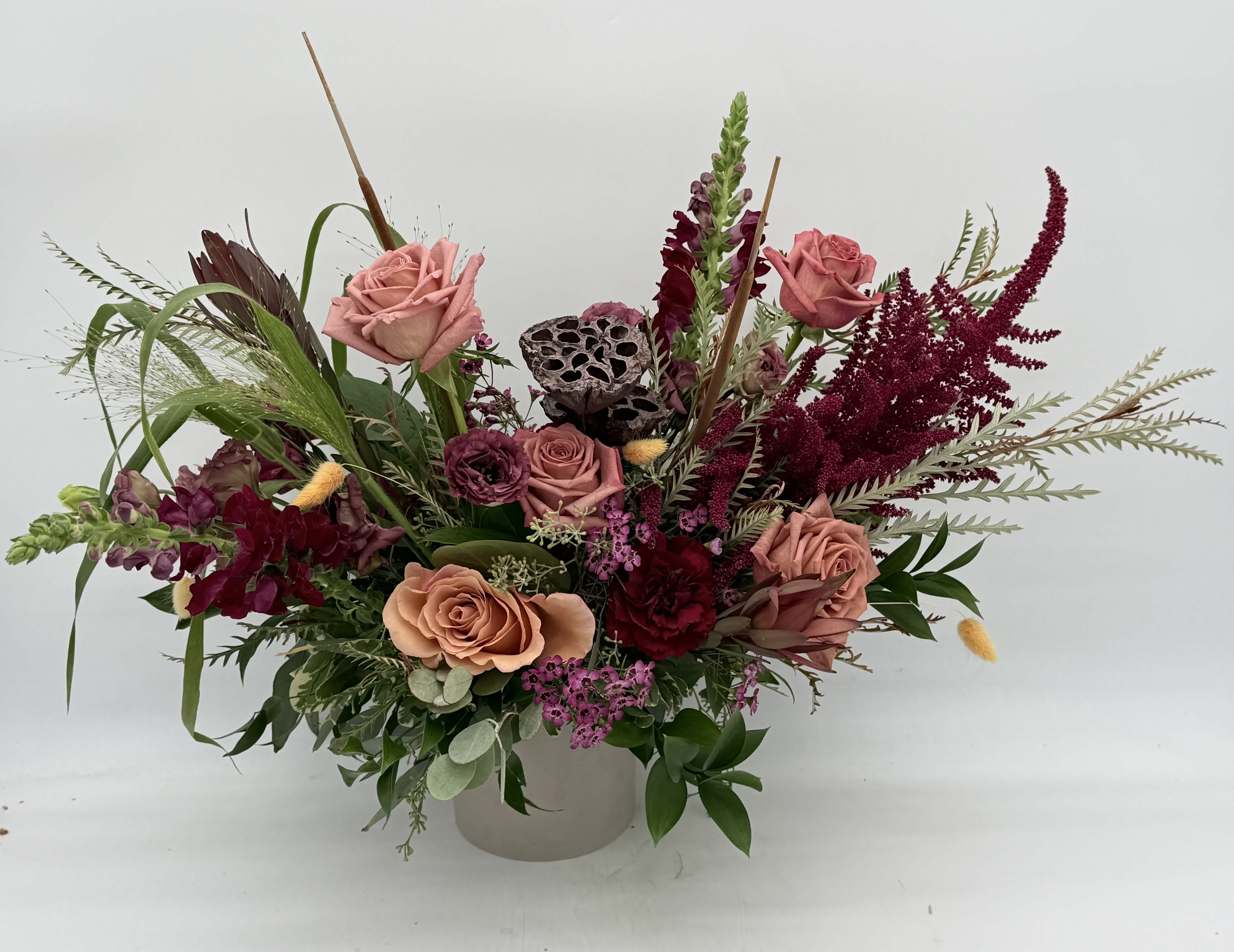 Mixed bouquet of pink roses and burgundy flowers in a white vase