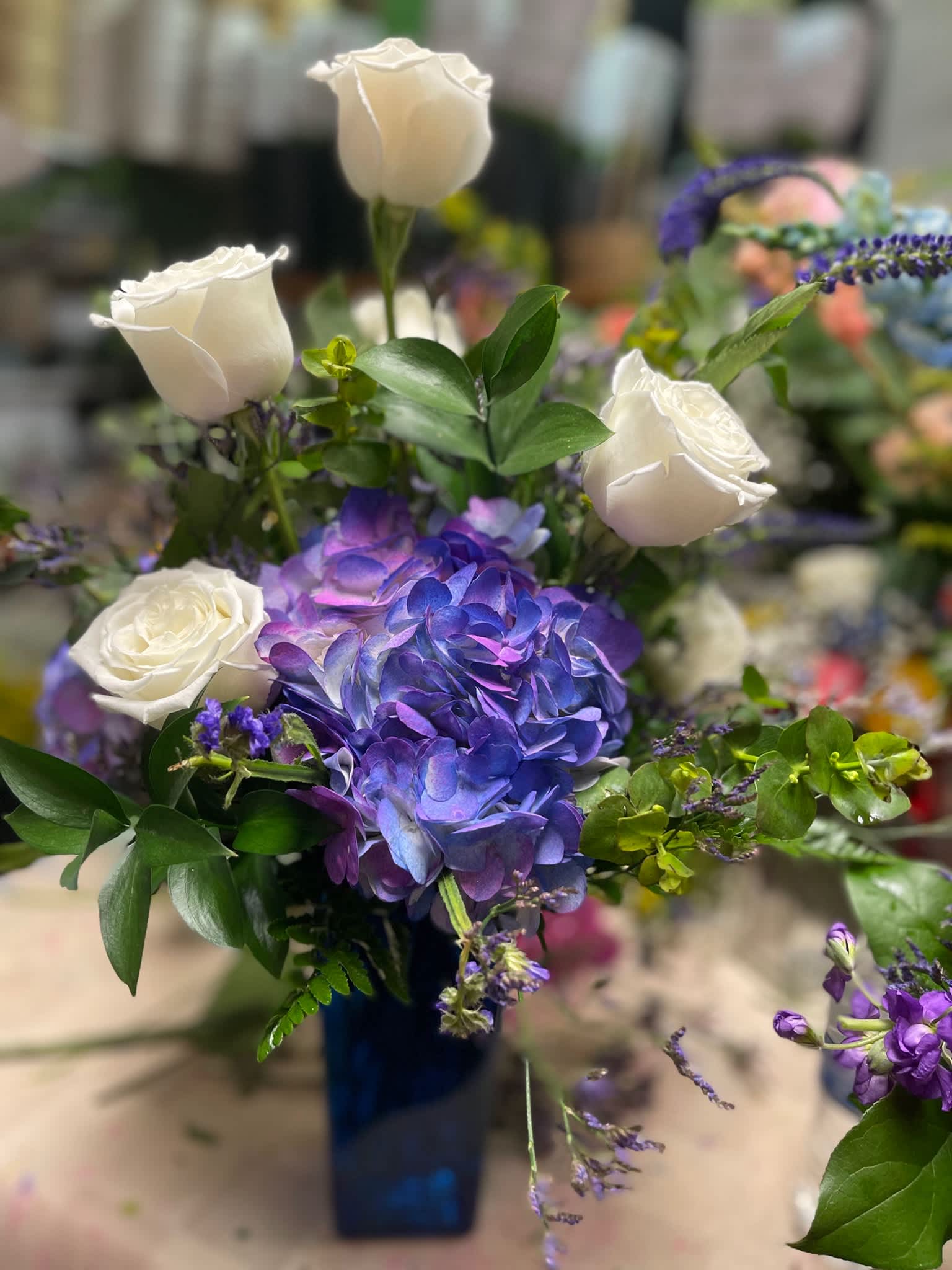 White roses and purple hydrangea in a blue vase