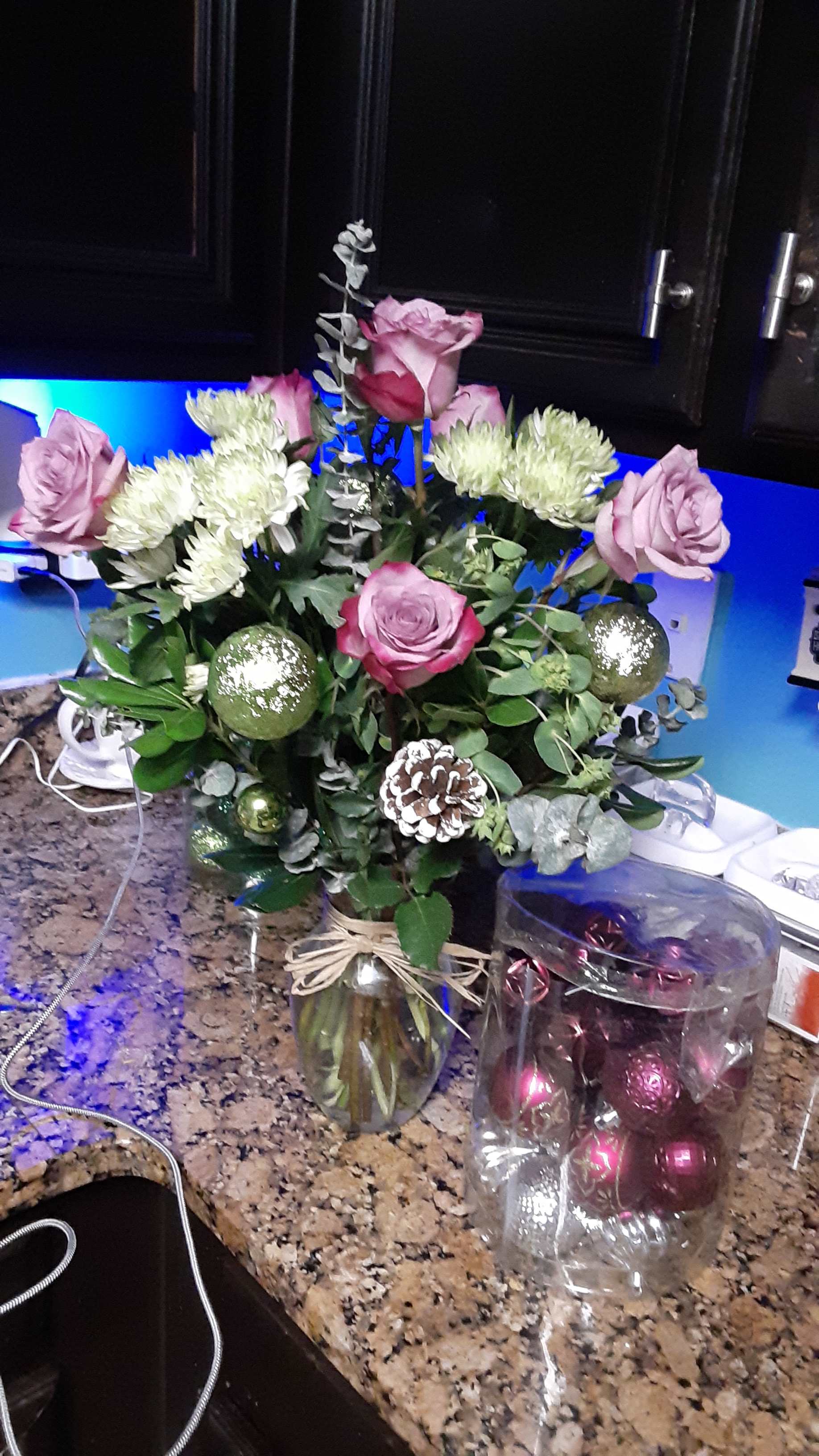 Pink roses and white chrysanthemums in a glass vase with ornaments