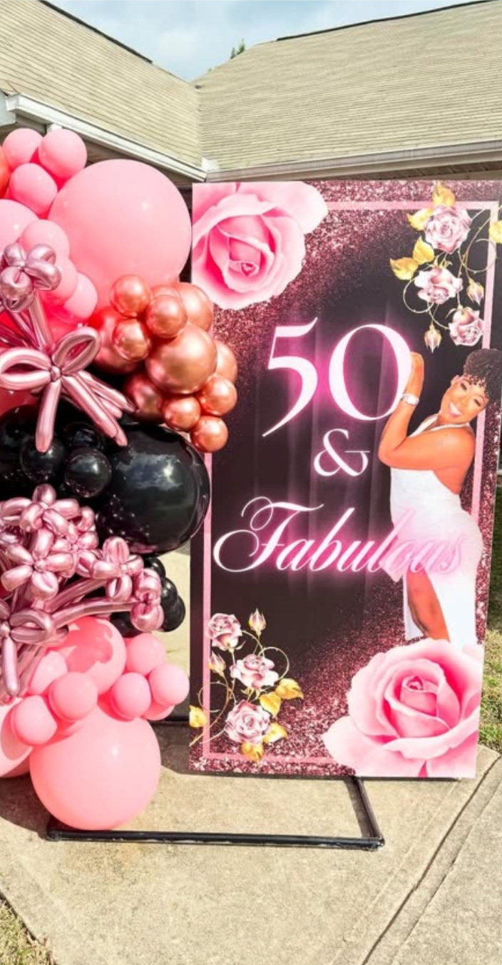 Pink and black balloon display beside a "50 &amp; Fabulous" party sign