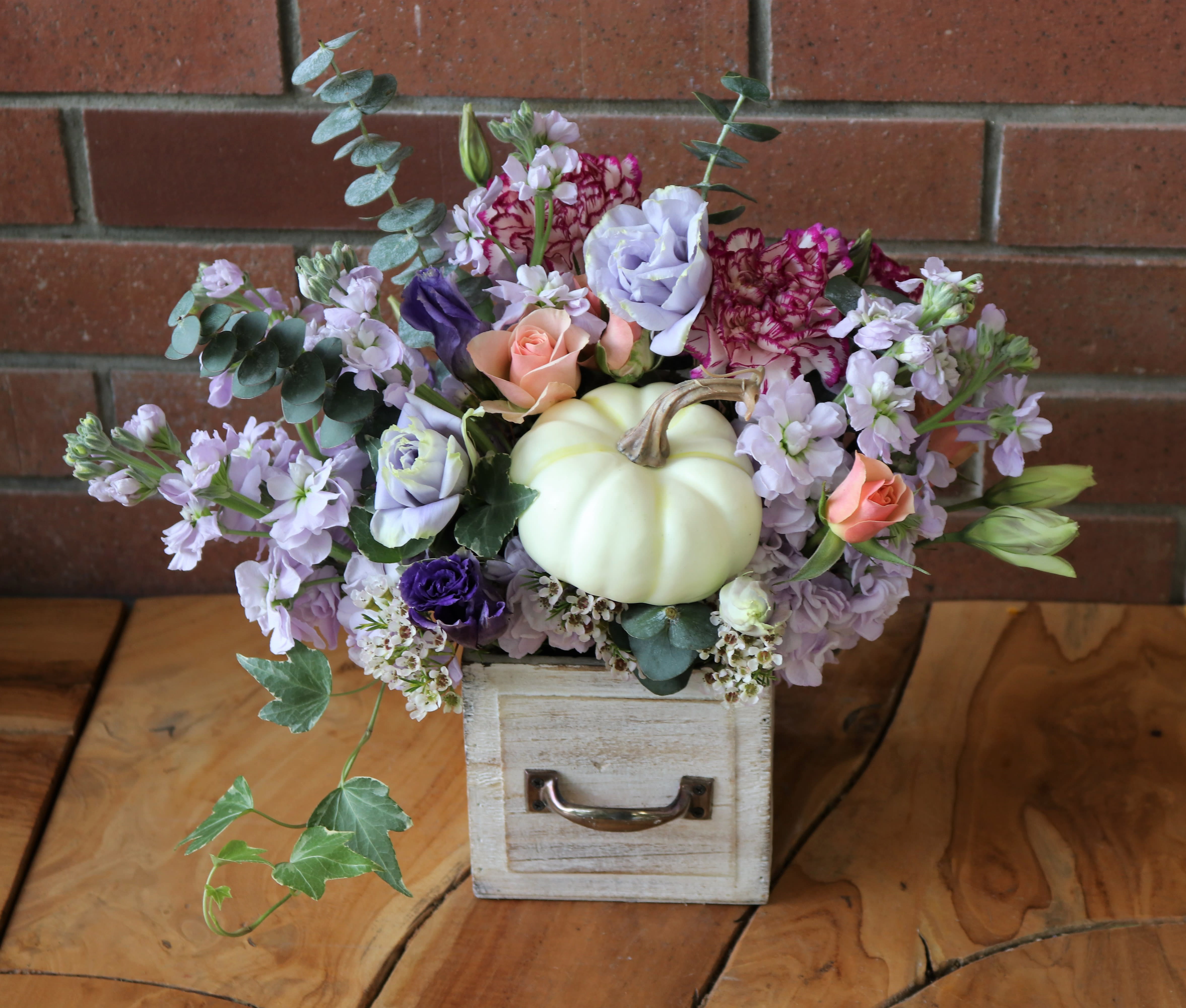Pastel floral arrangement with a white pumpkin in a small wooden drawer box