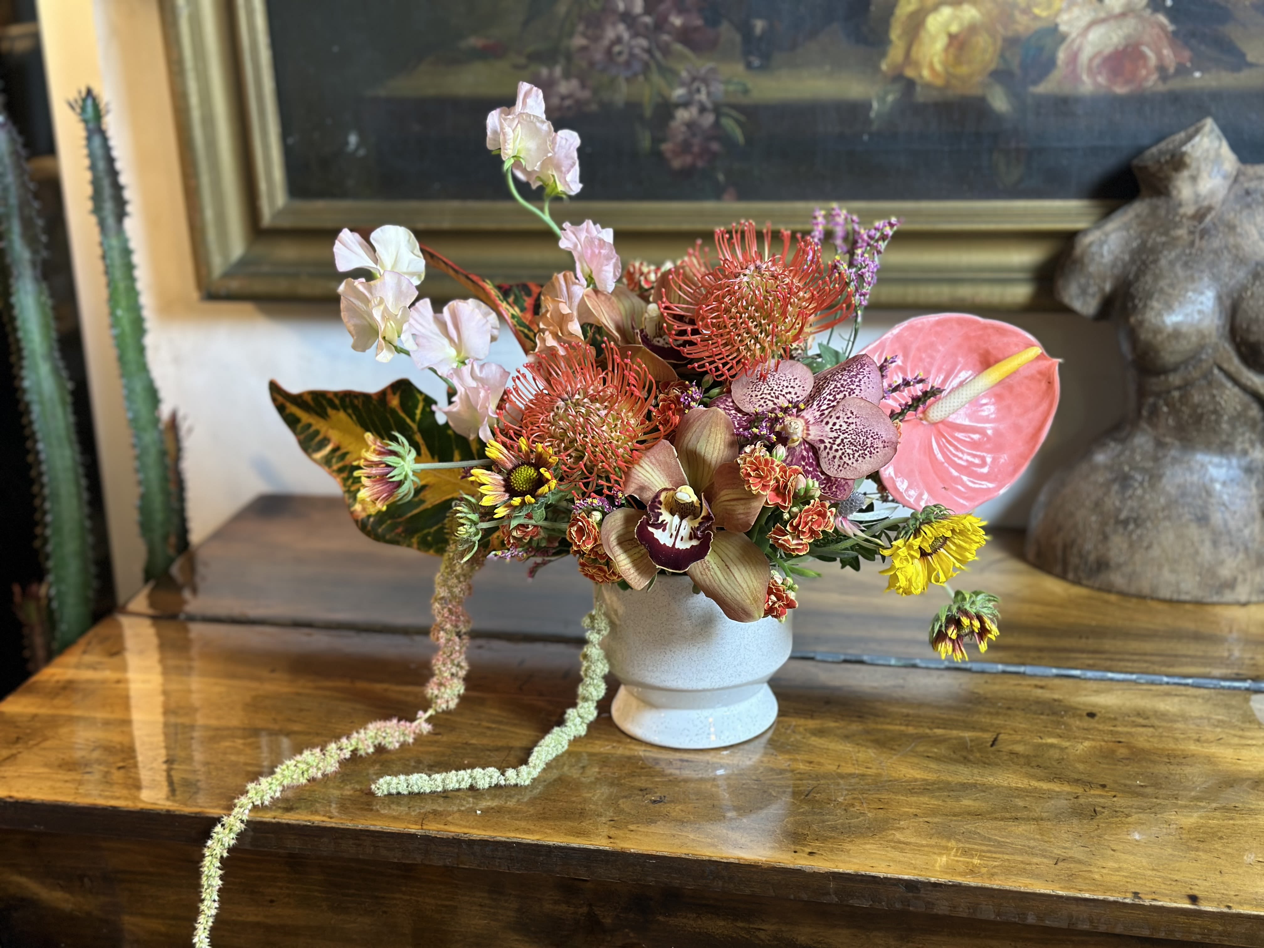 Tropical floral arrangement in a white vase with pink anthurium and orchids