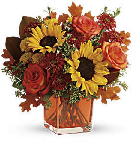 Bouquet of sunflowers and orange roses in a square glass vase