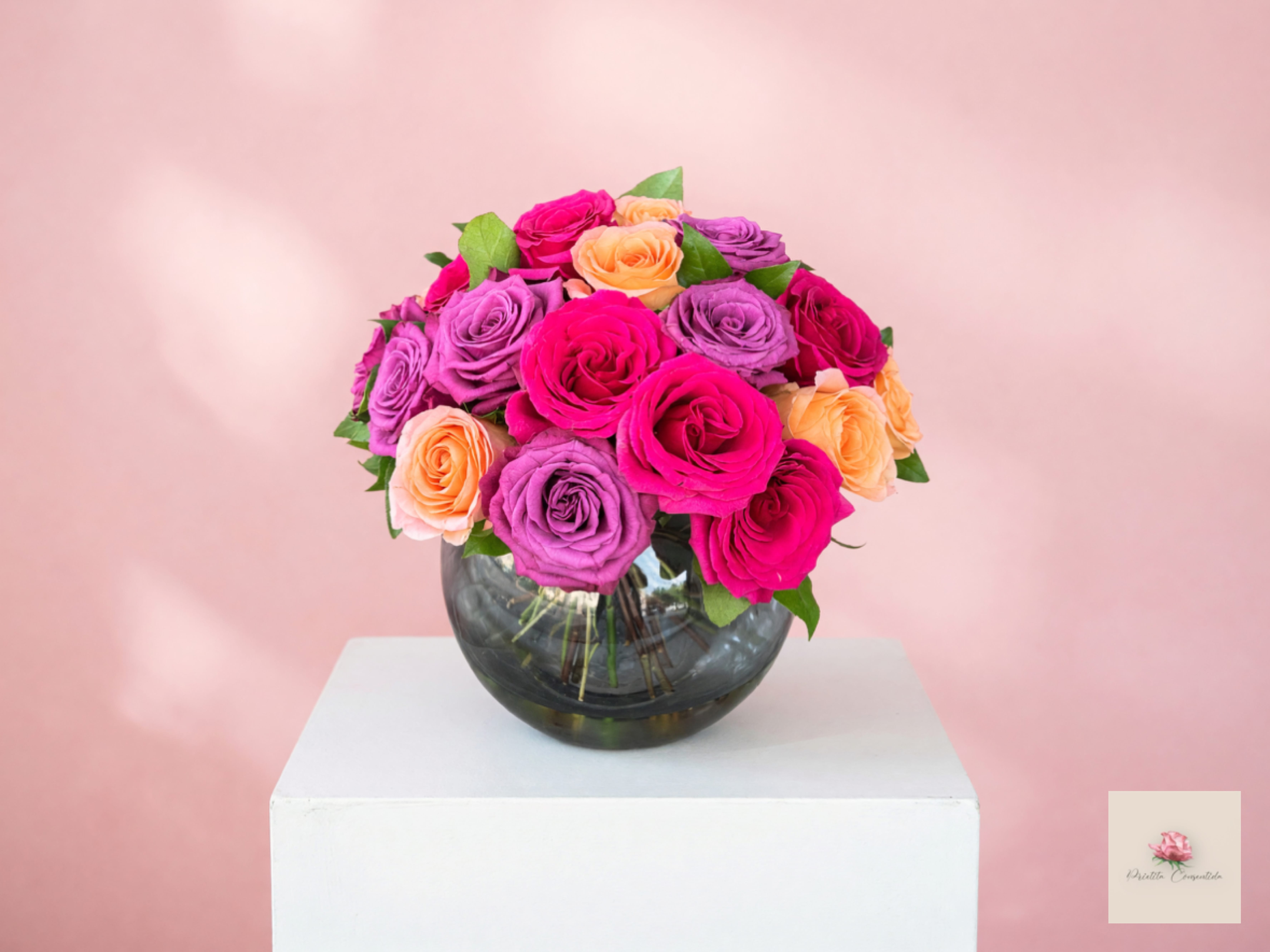 Bouquet of pink, purple, and peach roses in a round glass vase