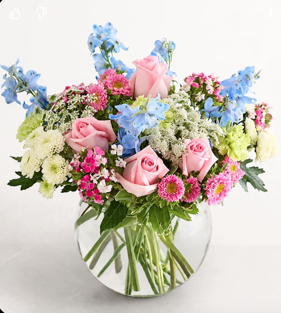 Tuesday's Gone - A charming mix of soft pink, blue, white, and green blooms designed in a clear glass vase. This cheerful arrangement features premium roses accented with seasonal flowers and lush greenery, creating a fresh, garden-inspired look!