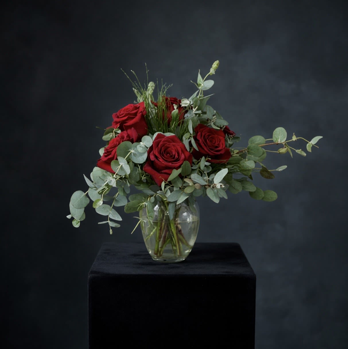 Simply Romantic - Let your love speak for itself with our Simply Romantic arrangement. This timeless design features lush red roses accented with soft eucalyptus and airy greenery, arranged in a clear glass vase. Elegant and understated, it’s the perfect gesture for anniversaries, just because, or any heartfelt moment.  Vase style and greenery may vary based on availability. 