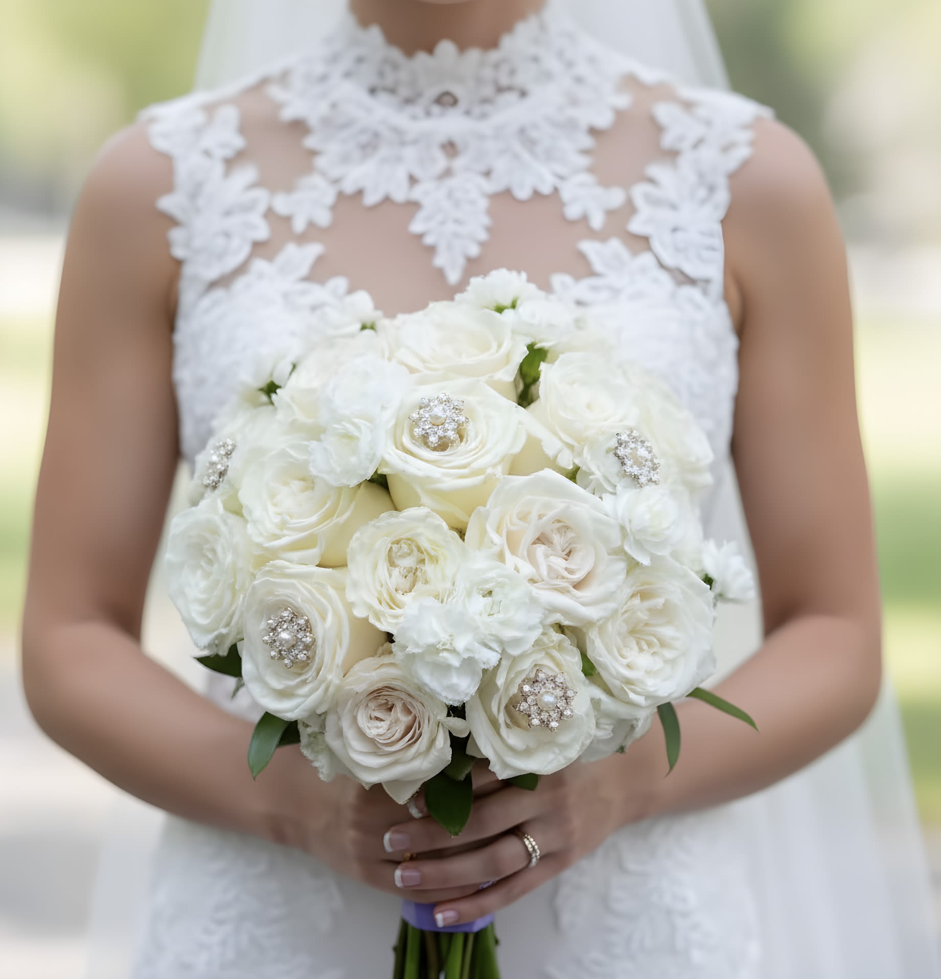 Bride holding a white rose bouquet with jeweled accents