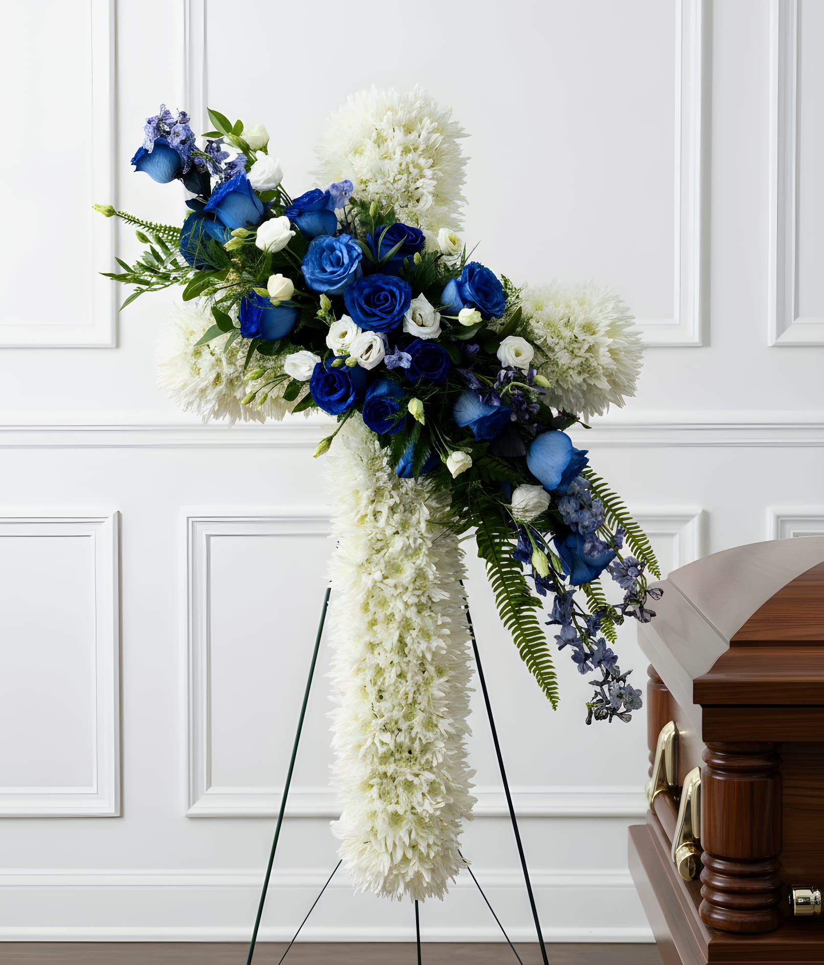 Blue and white funeral spray on a stand beside a casket