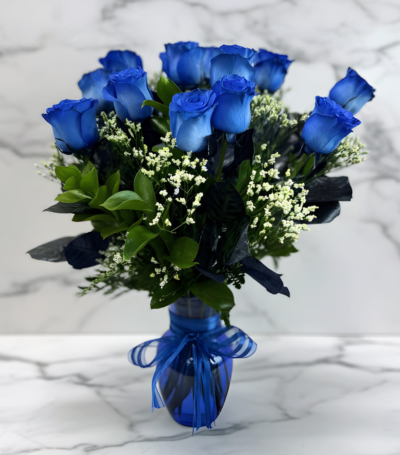 Blue roses in a glass vase with a blue ribbon