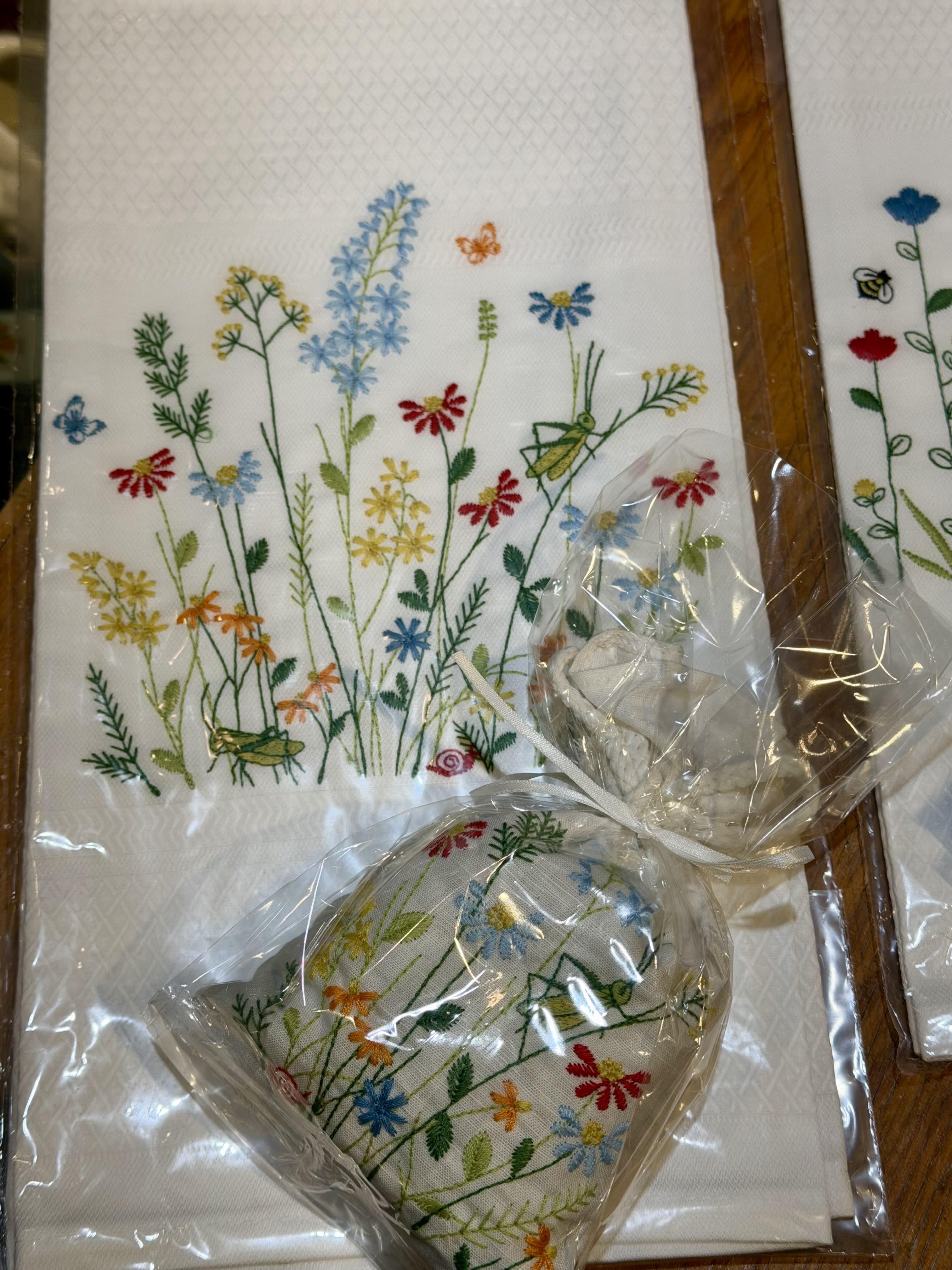Embroidered floral napkins and a matching heart-shaped pouch in plastic wrap